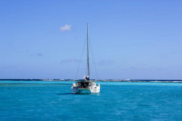 Catamaran sailing across bright turquoise coral-reef waters