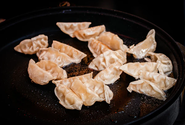 Pan-fried gyoza dumplings cooking on a griddle