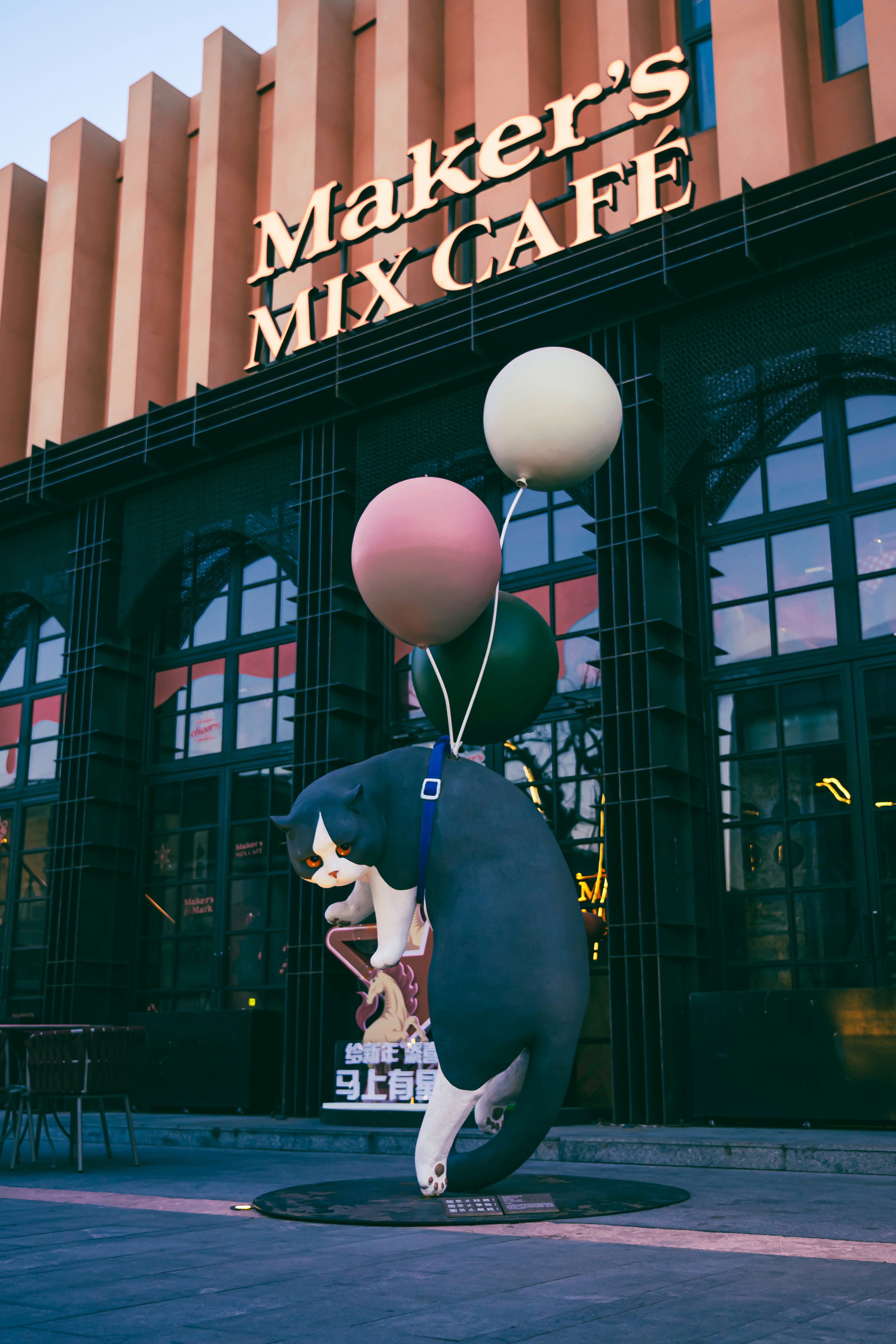 Riesige aufblasbare Katze mit Luftballons vor dem Café