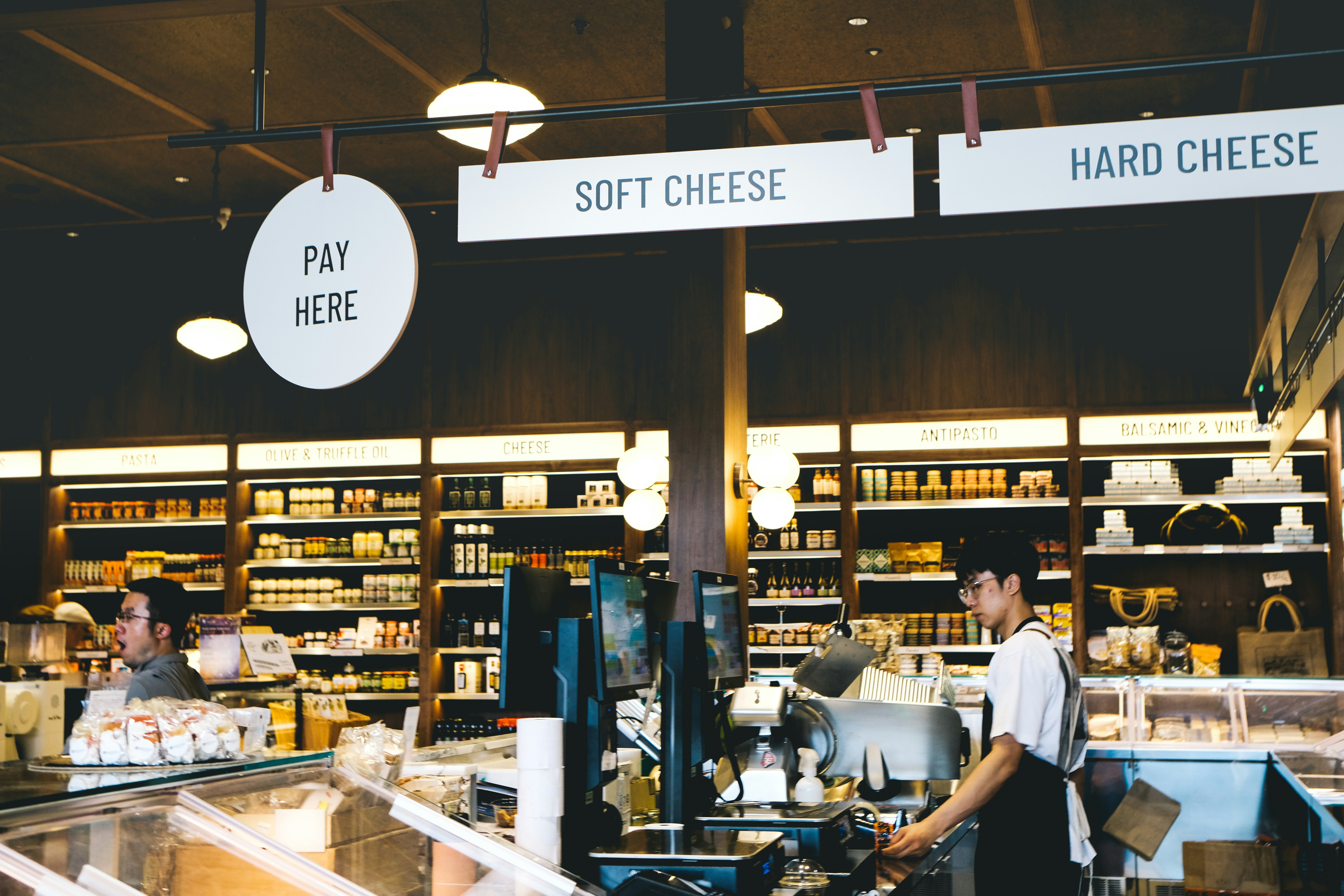 Employees working at a cheese counter in a store.