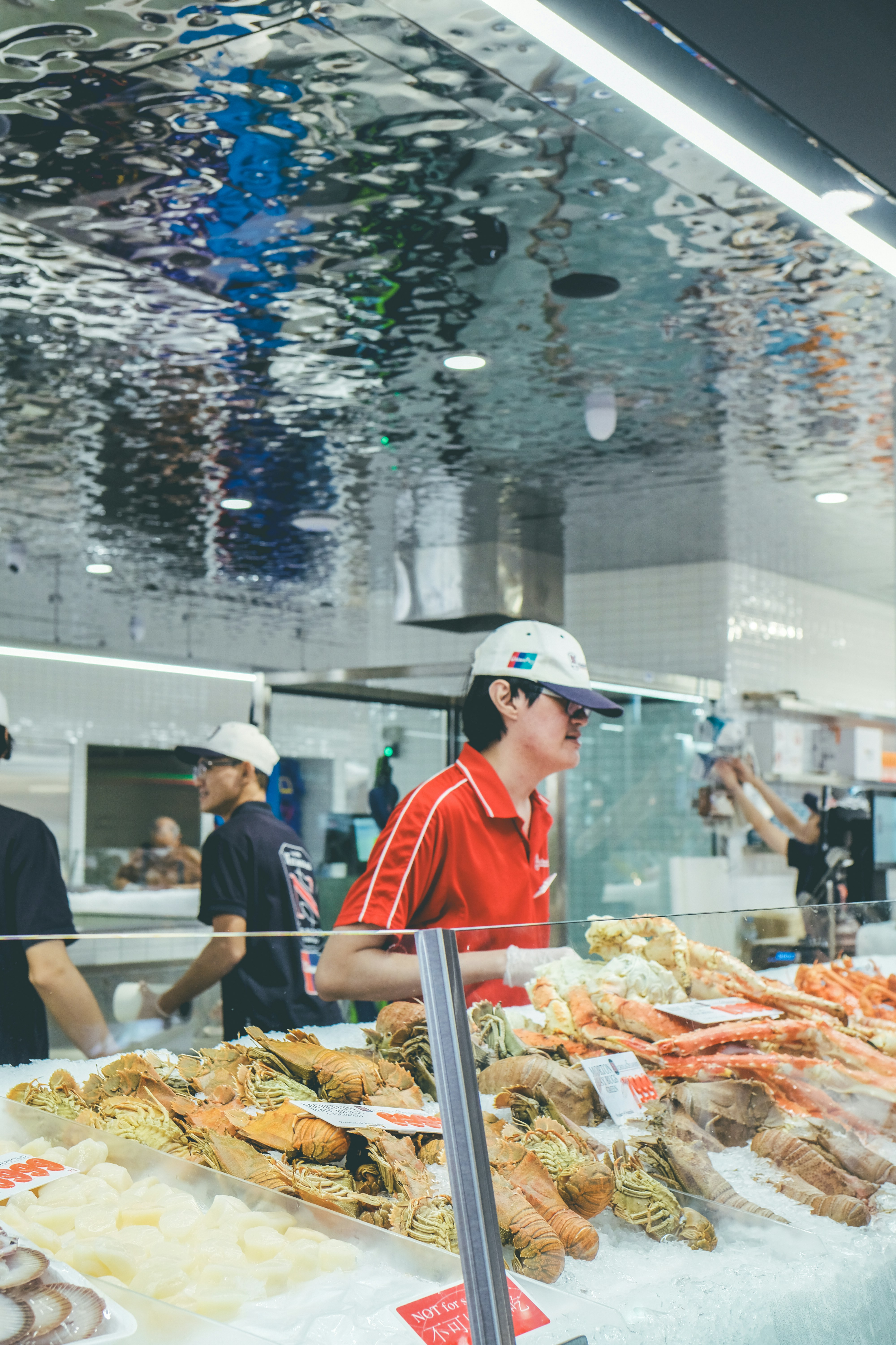 Workers behind a seafood display with lobsters and crabs.