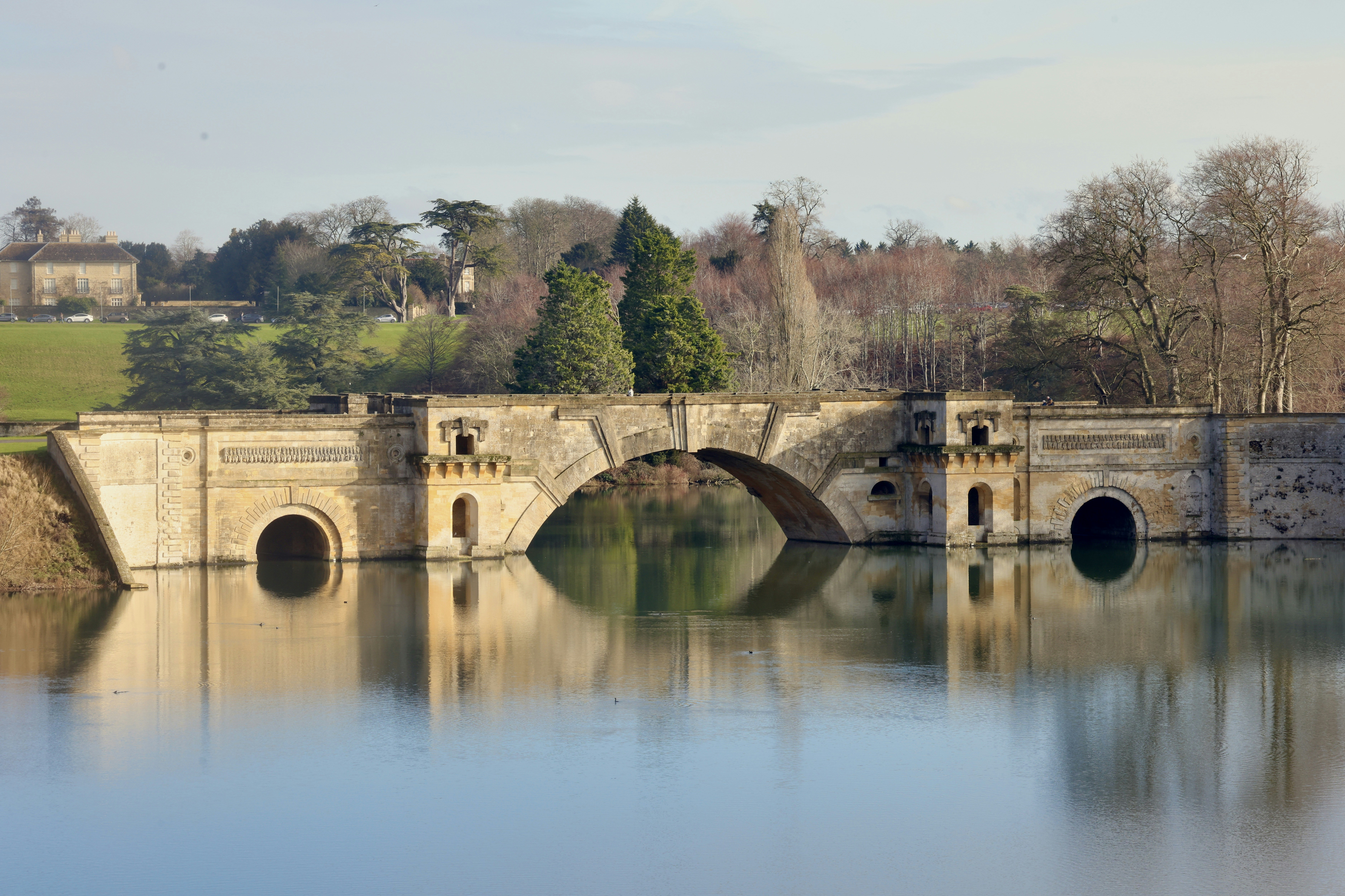 A stone bridge with arches over calm water