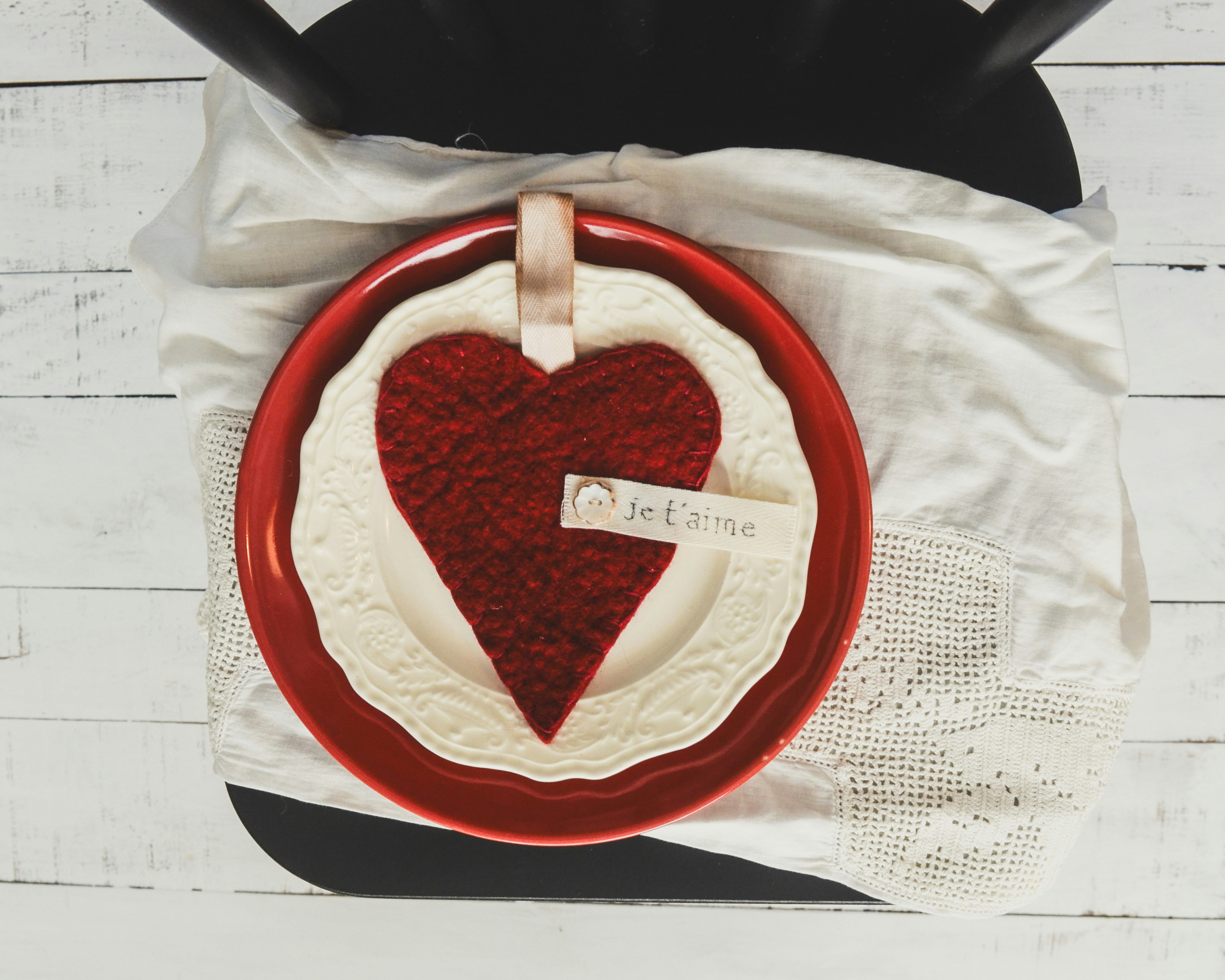 Decorazione a cuore rosso su un piatto con una tovaglia bianca