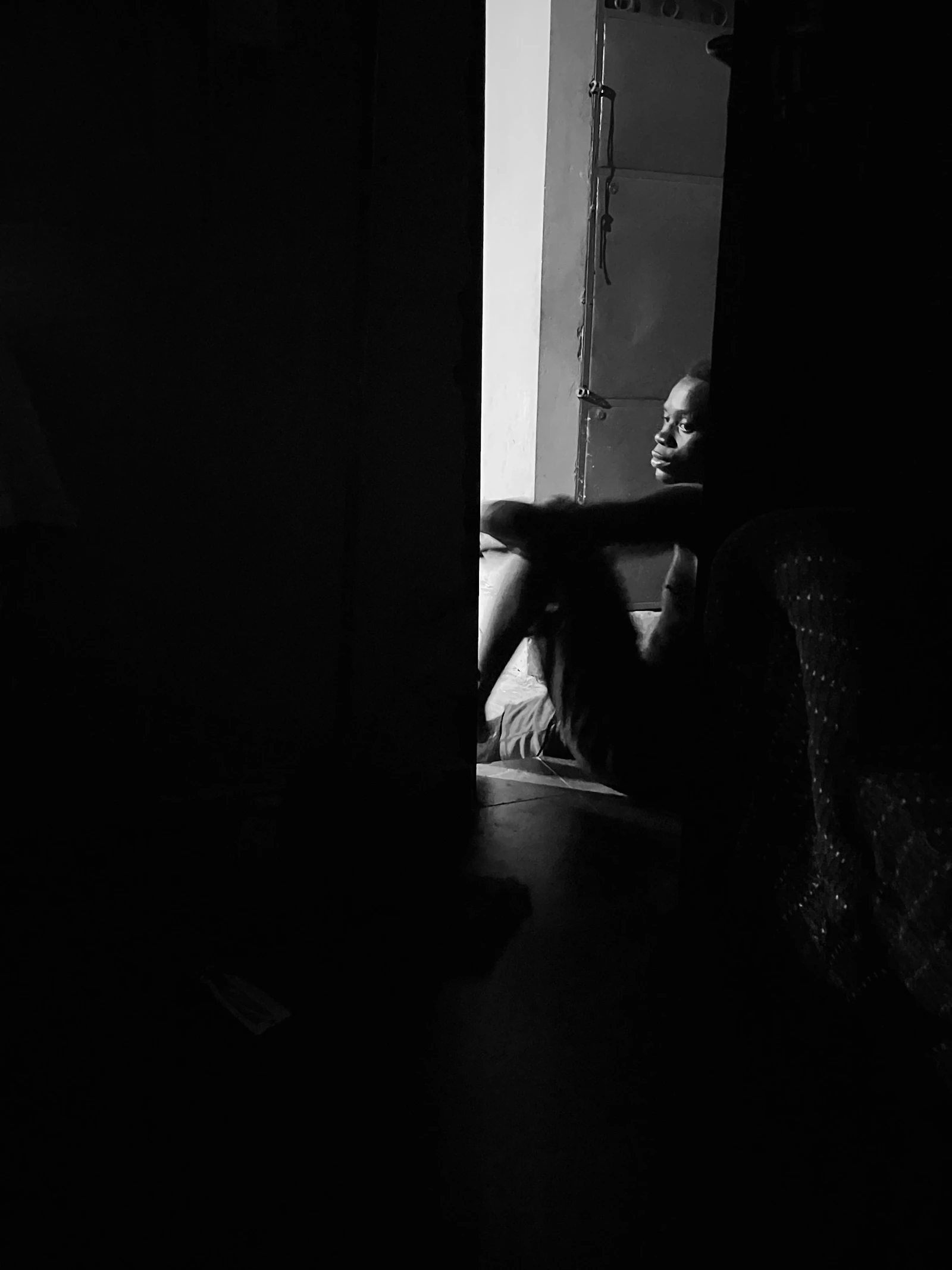 Person sitting quietly beside a window in shadow, reflecting after a difficult relationship