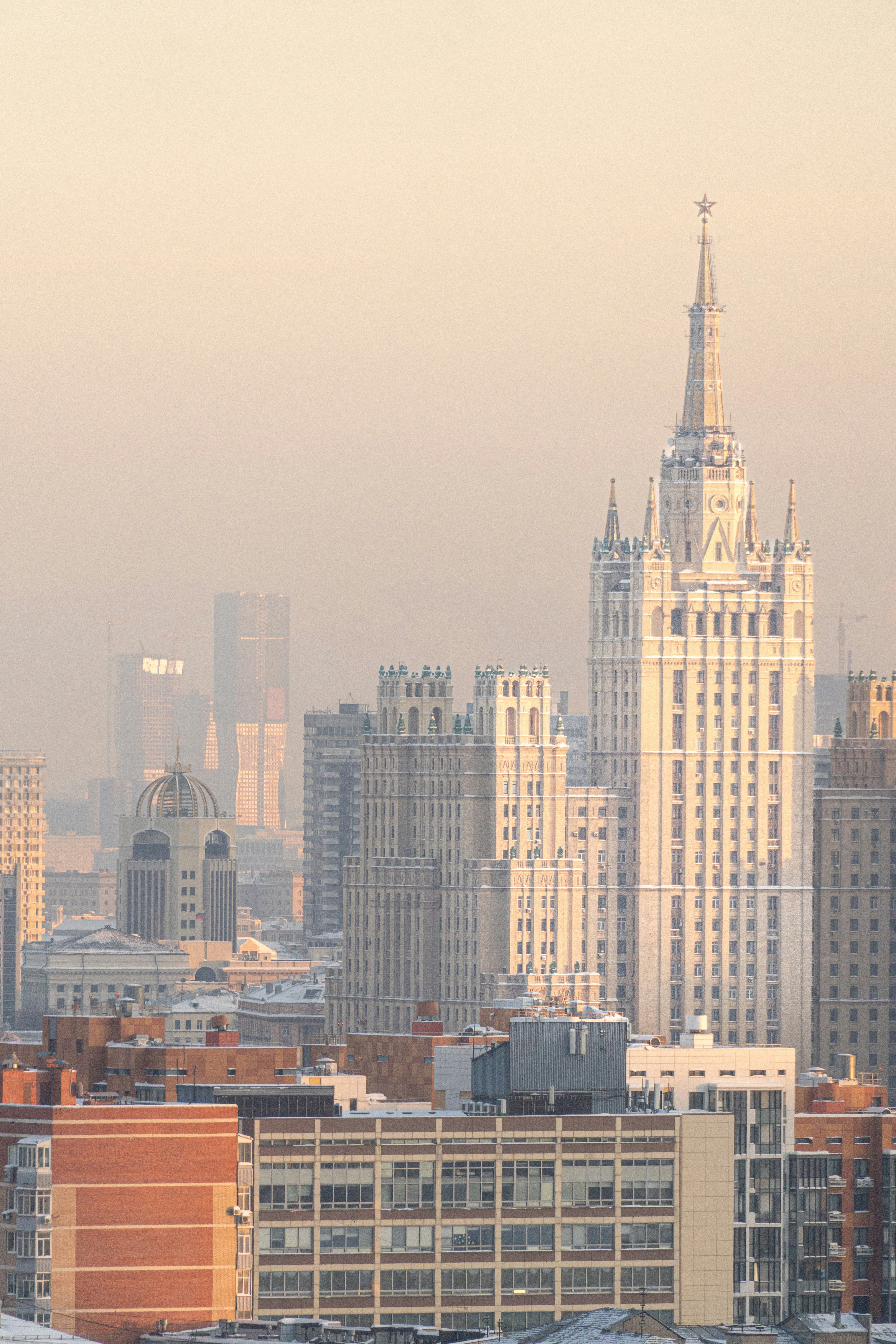Tall white skyscraper and buildings in hazy cityscape.