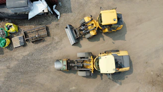 Two yellow construction vehicles parked on gravel