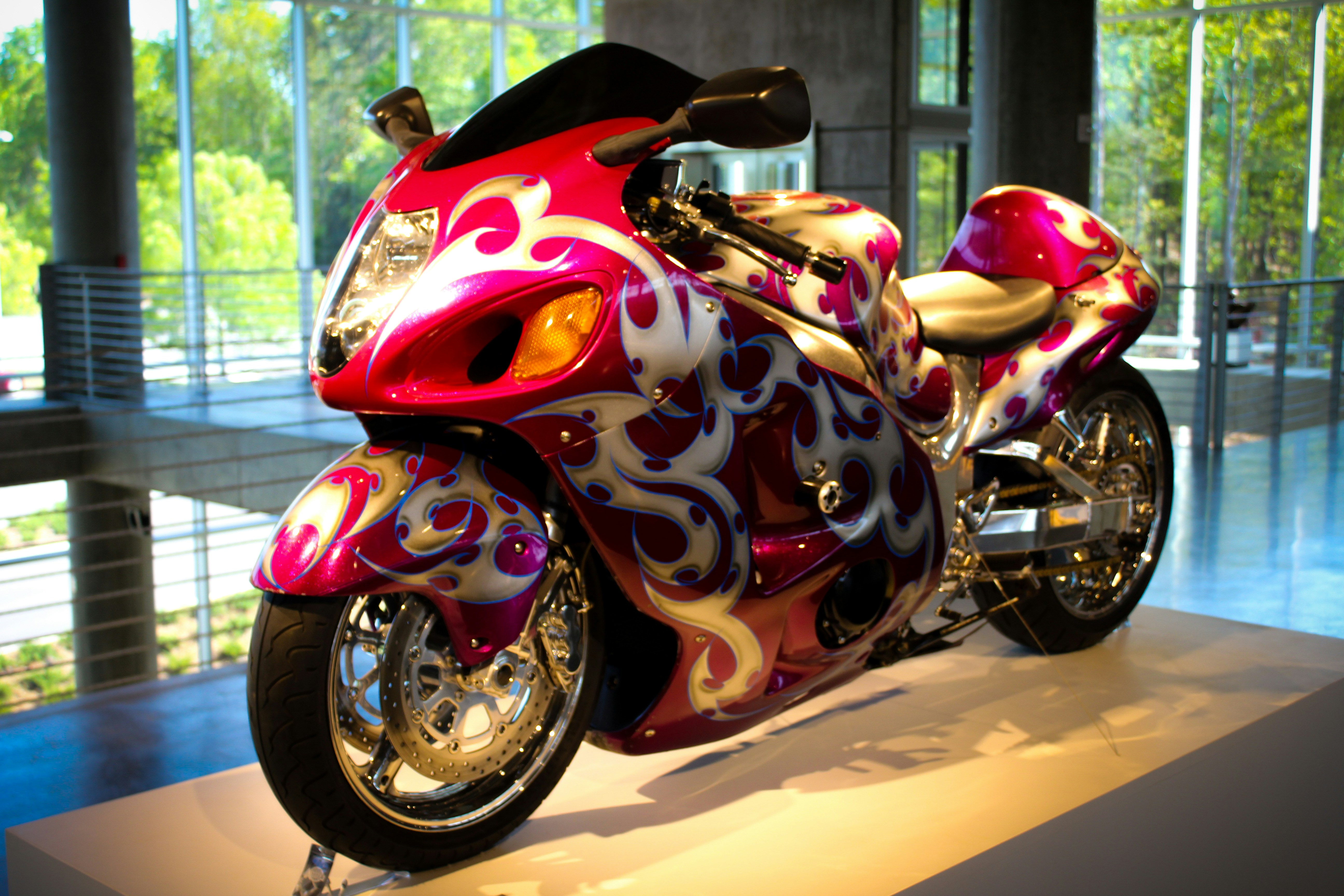 Une moto personnalisée rose et argent avec des motifs de flammes.