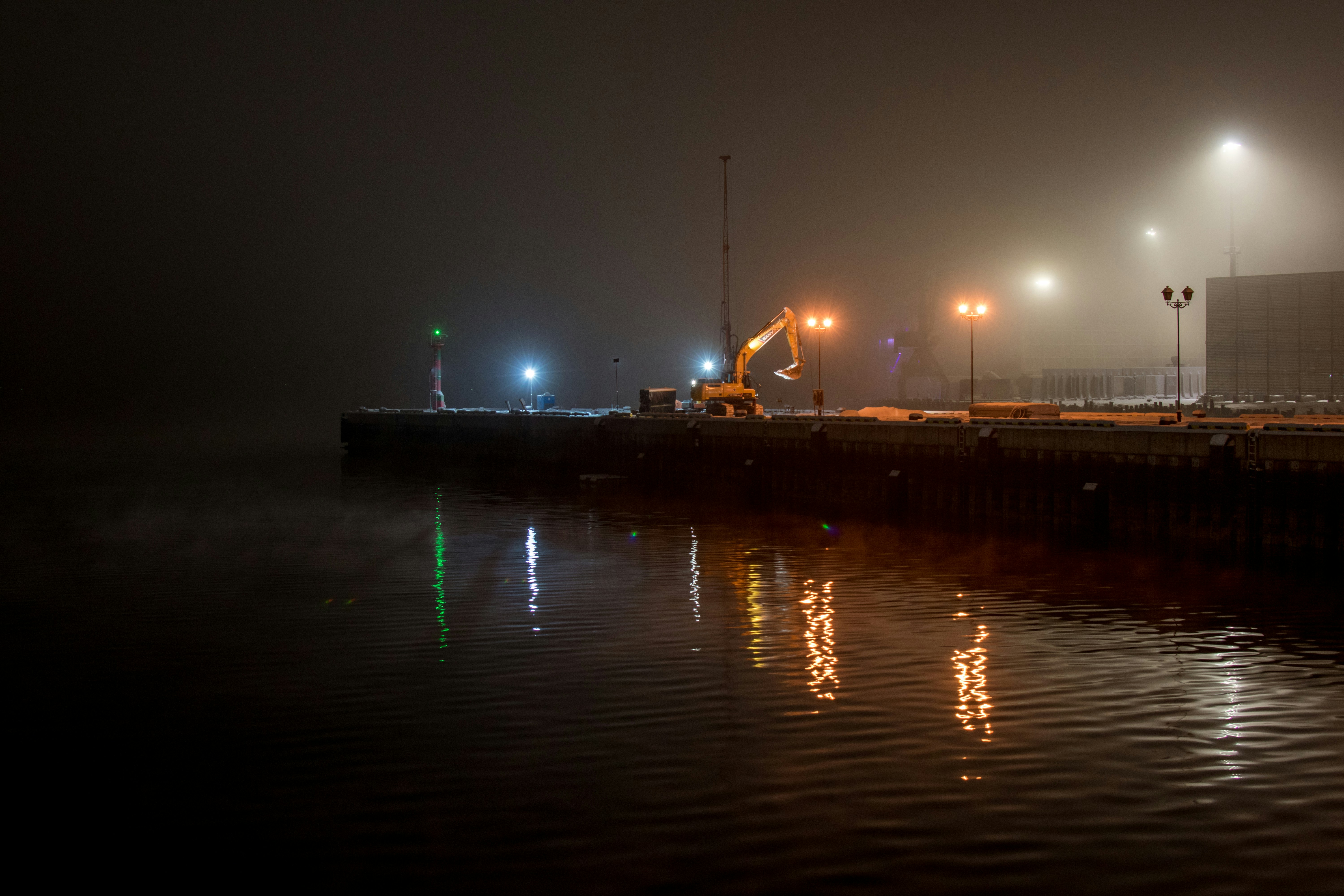 Porto enevoado com luzes brilhantes refletindo na água