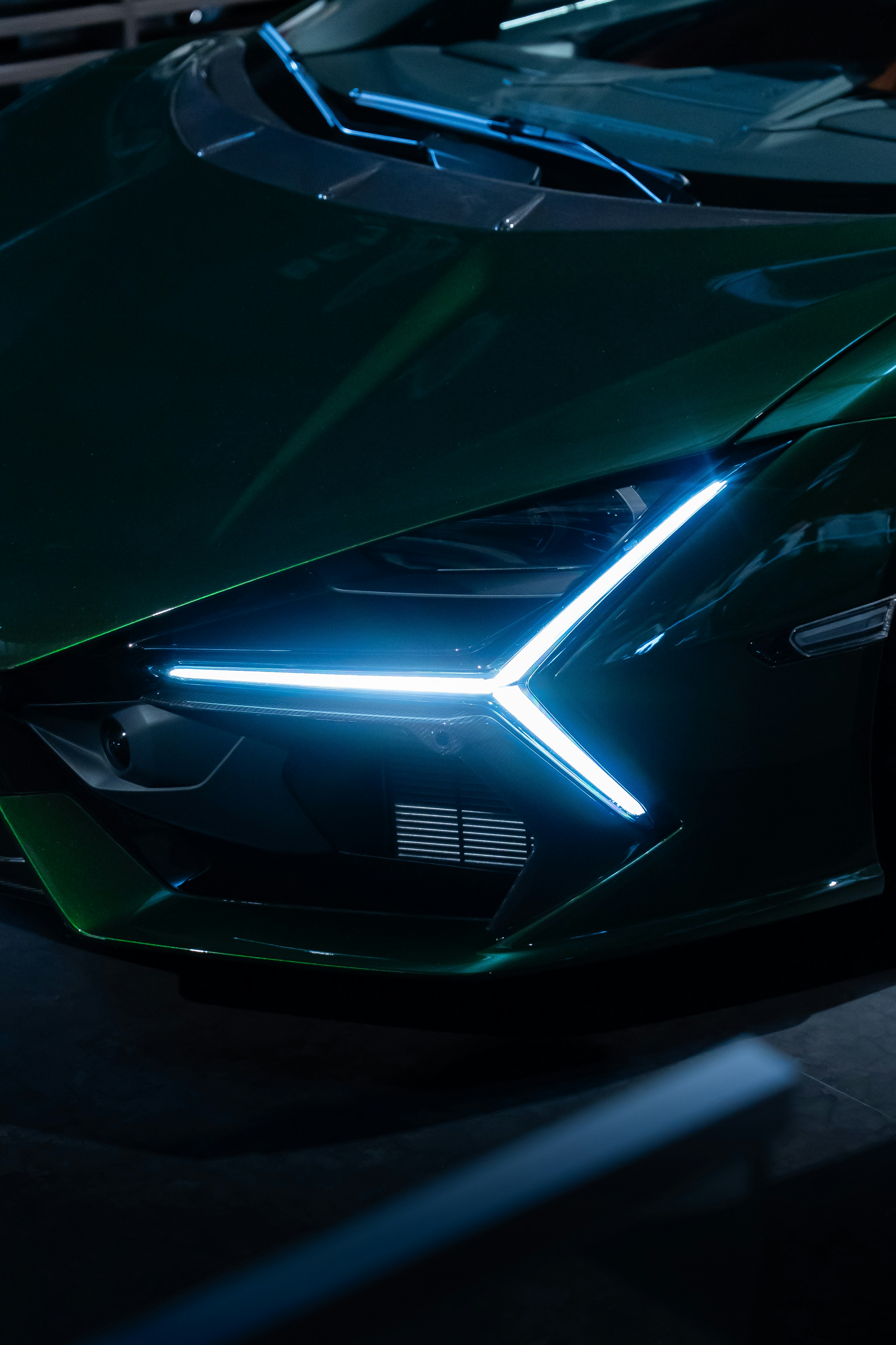 Close-up of a sleek, green sports car's headlight.