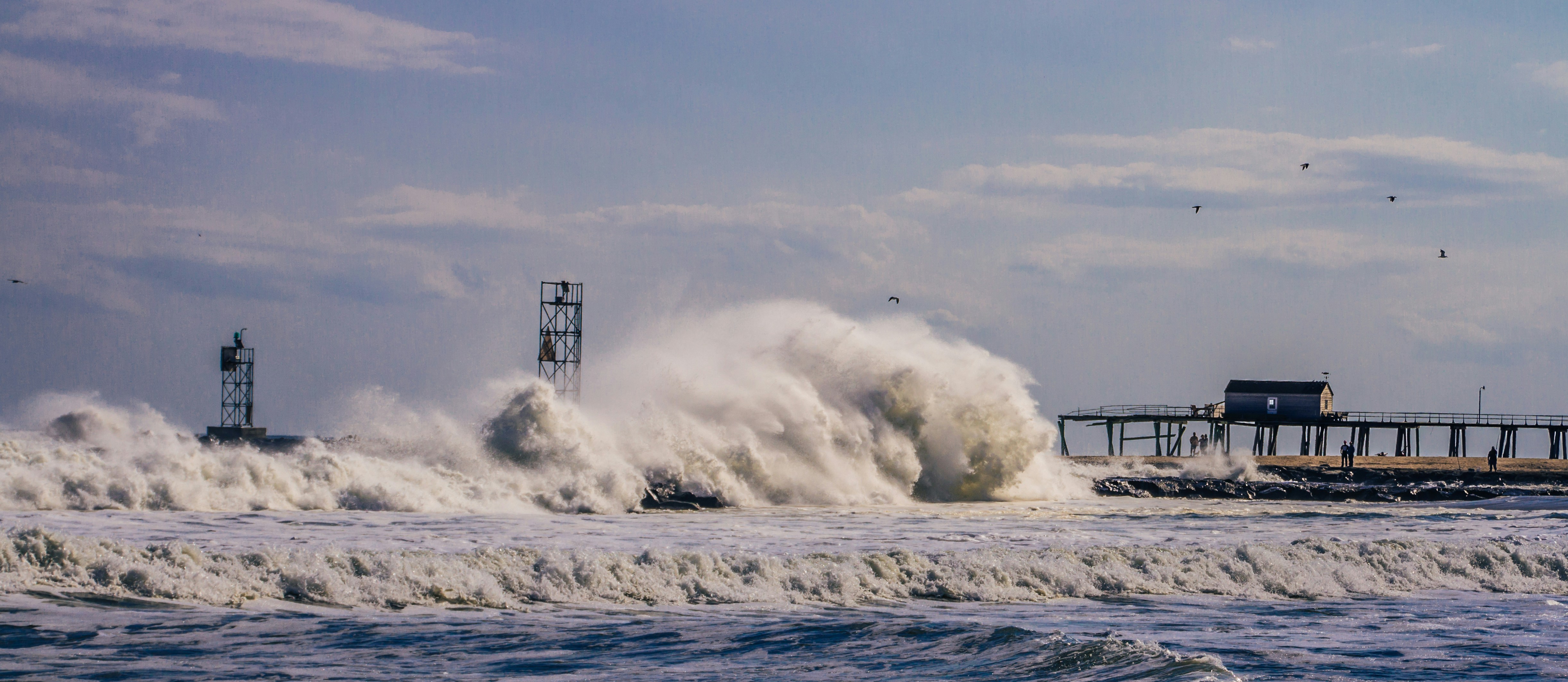Crashing ocean waves near a pier and navigation lights