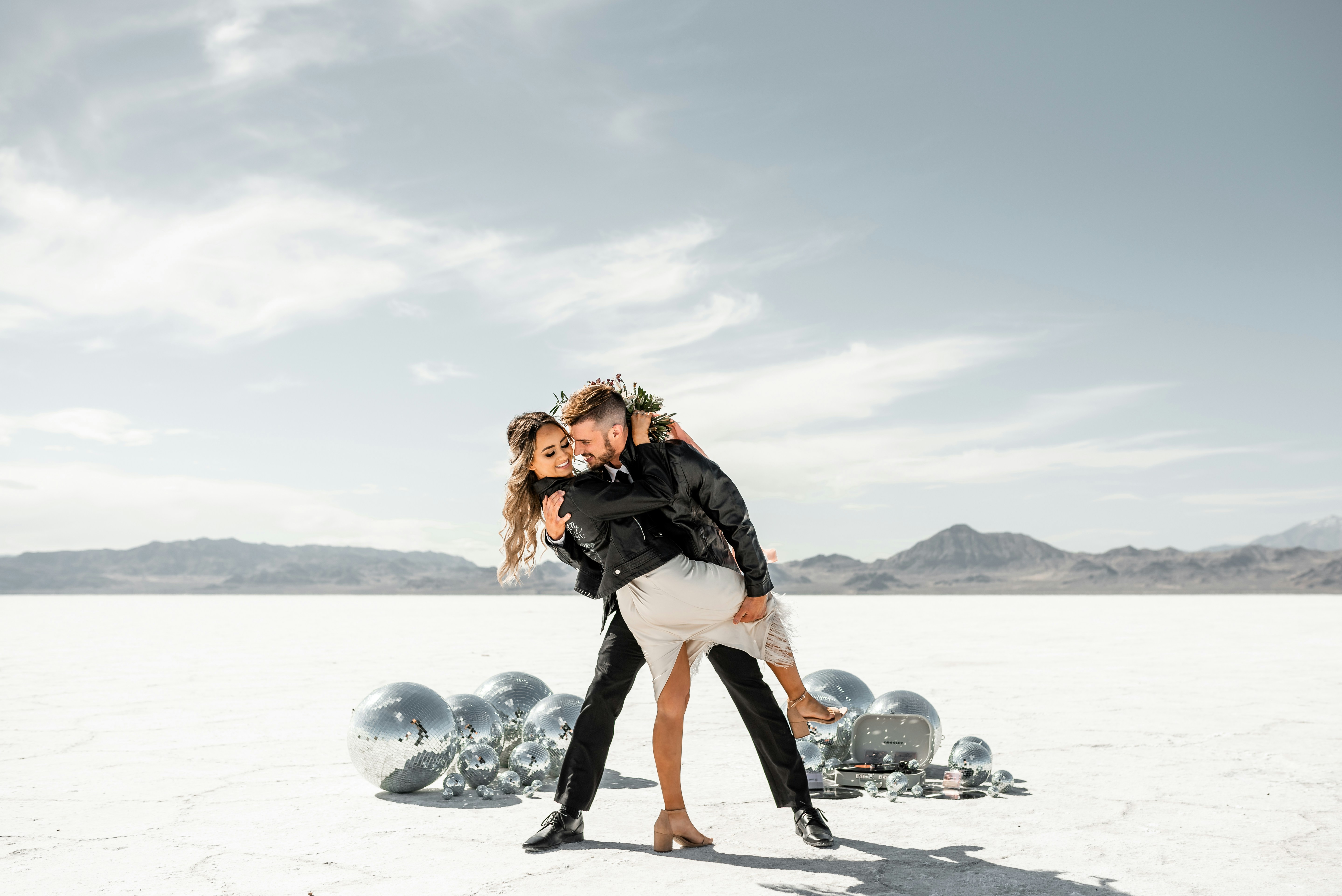 Paar, das in einer Wüste mit Discokugeln tanzt