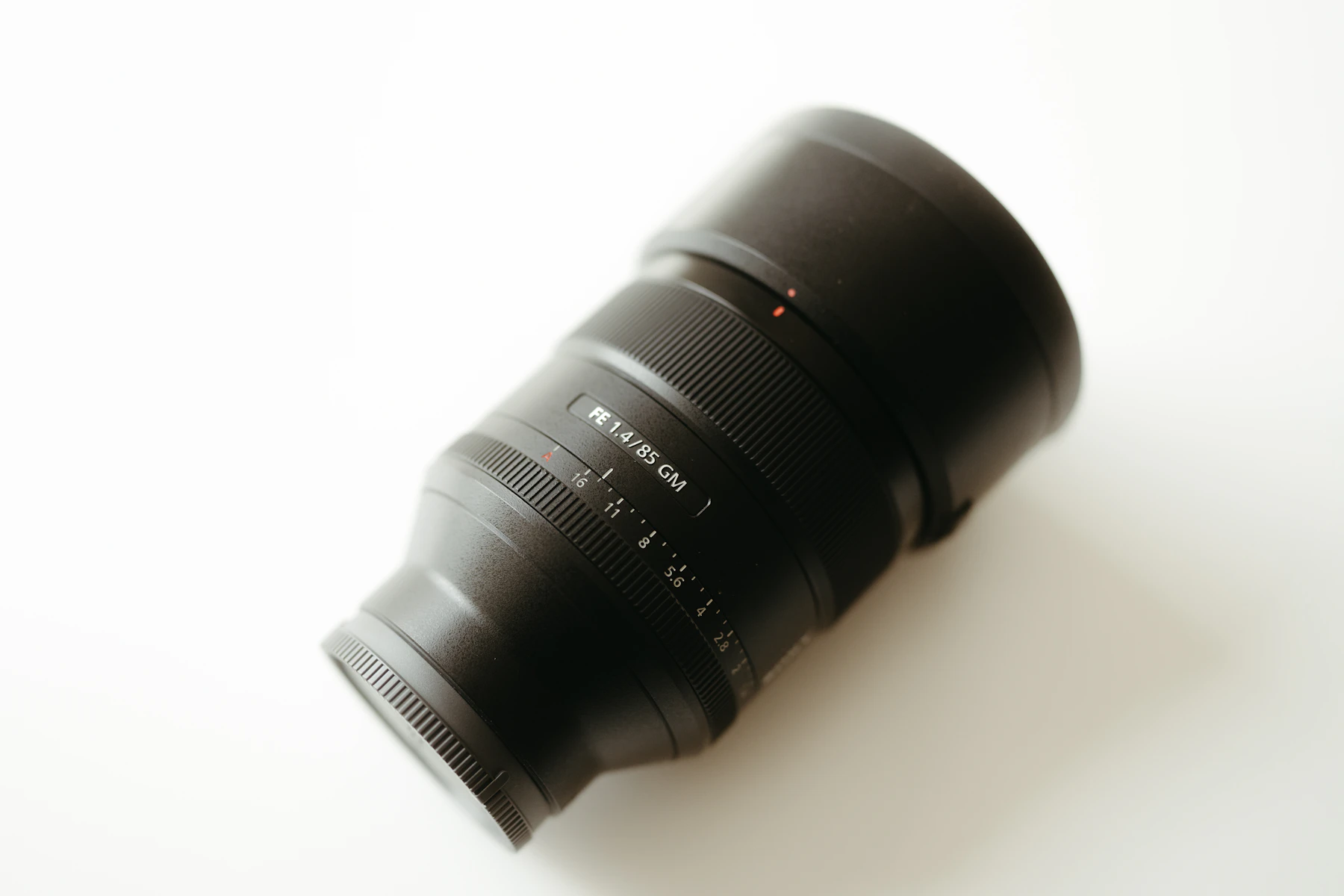 A black camera lens rests on a white surface
