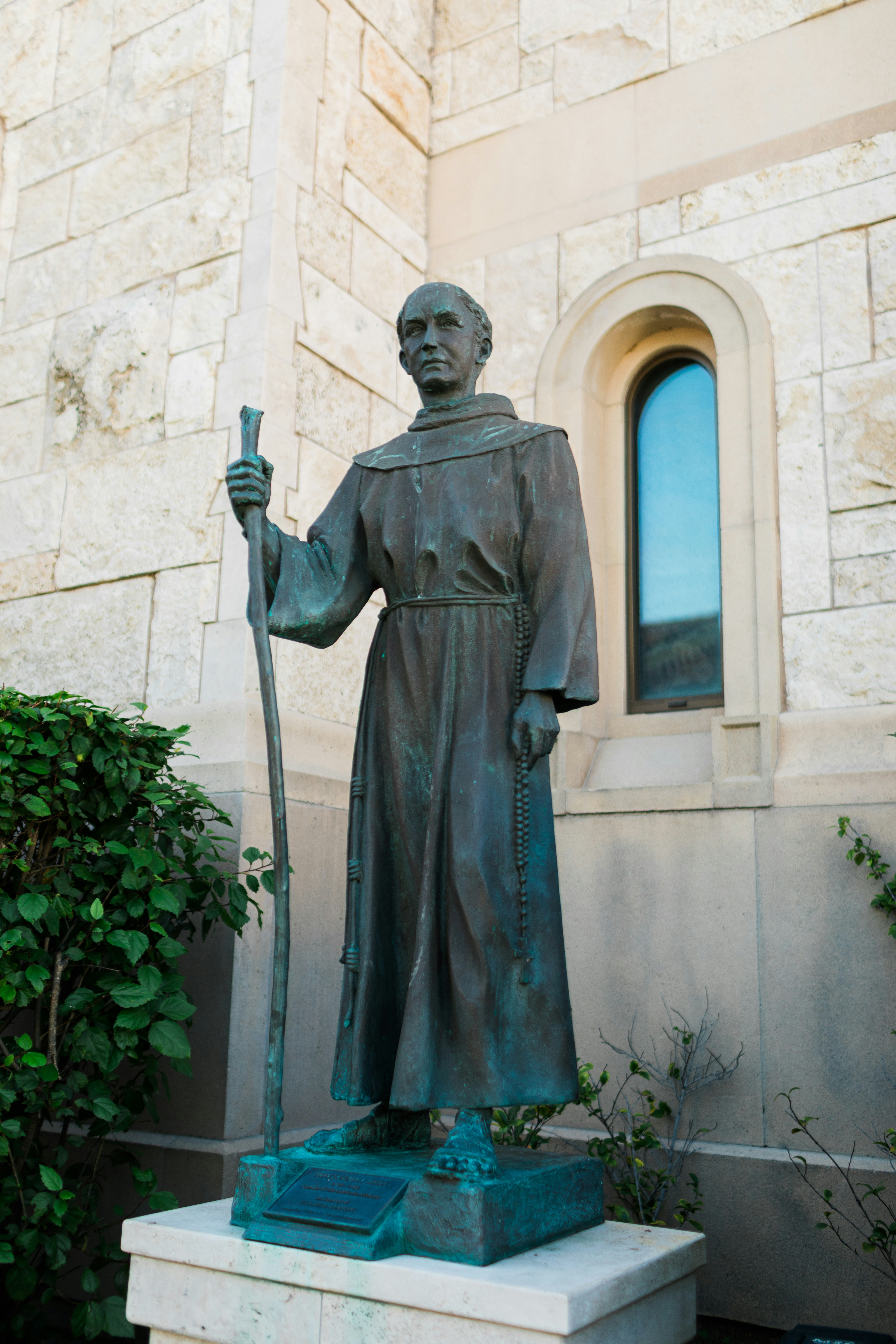 杖を持つローブをまとった男の青銅像。