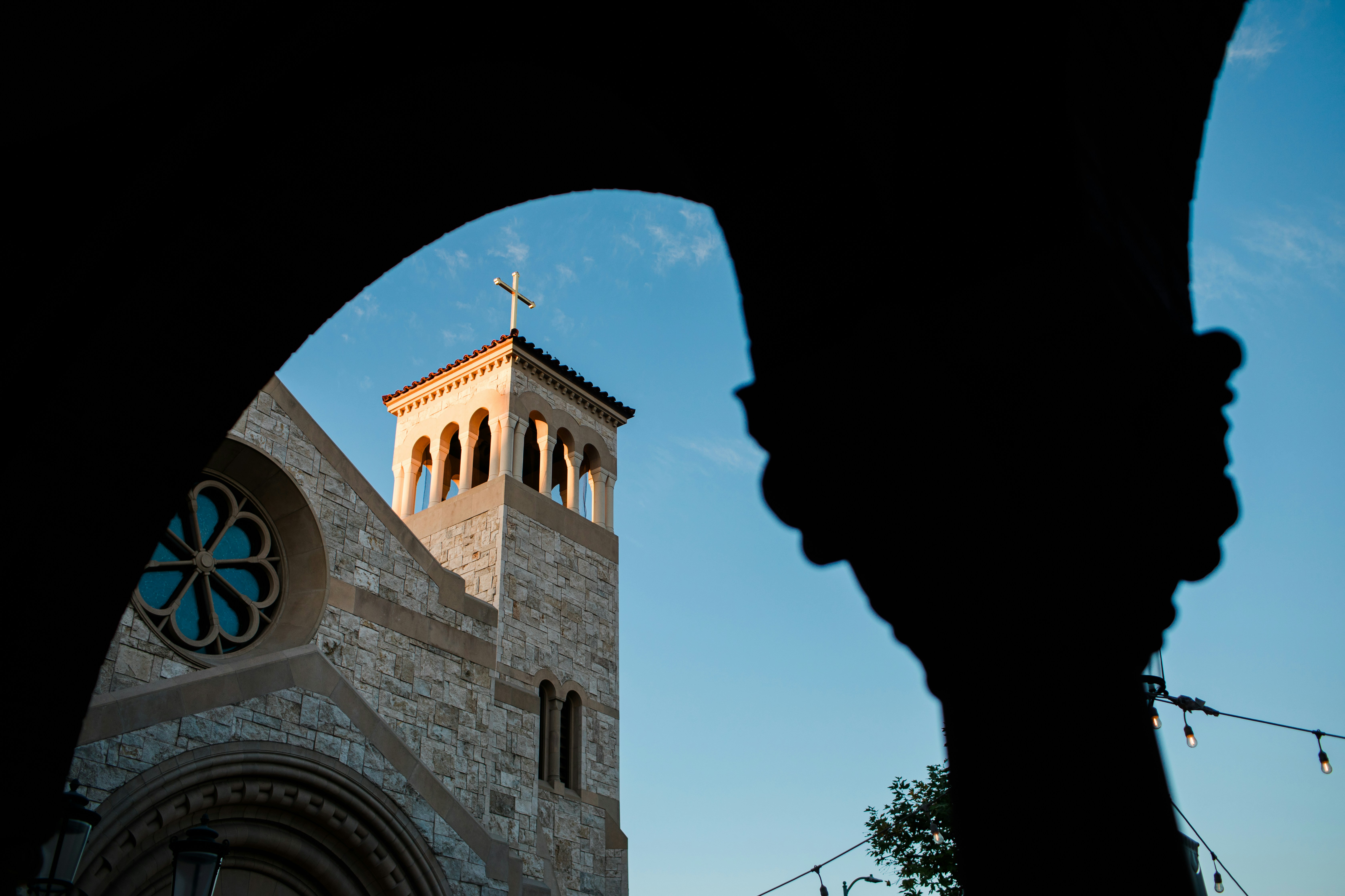 青空を背景にバラ窓のある石造教会の塔