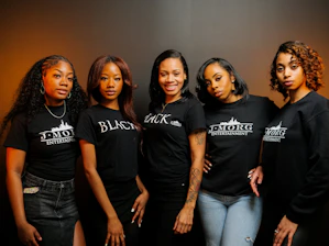 Five women posing together wearing black t-shirts.