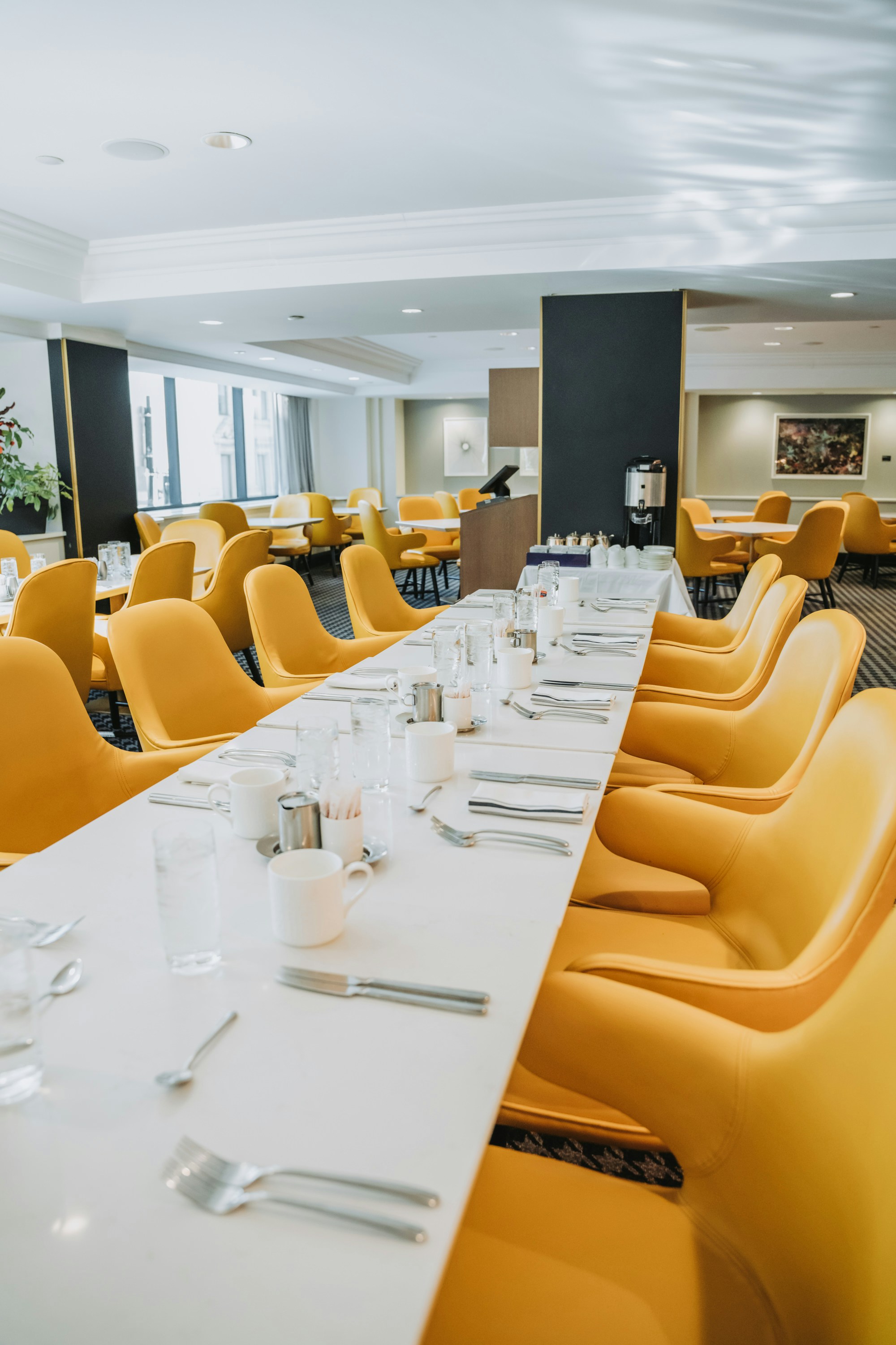 Long dining table set with yellow chairs in a restaurant
