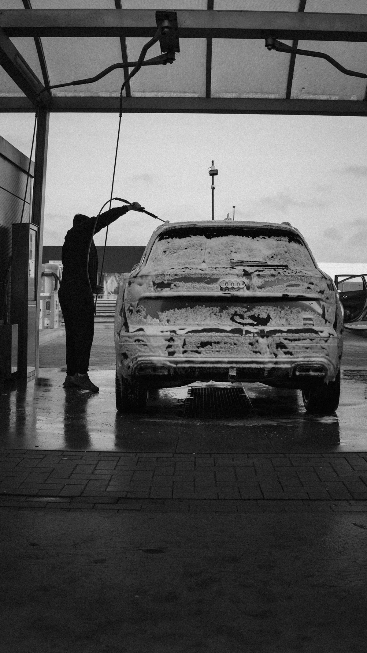 Person washing a car covered in foam during a professional hand wash