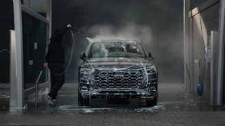 Person washing a black car with soap and water.
