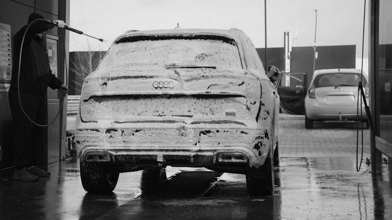 Car wash professional washing a vehicle covered in foam