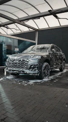 A dark suv covered in soap at a car wash.