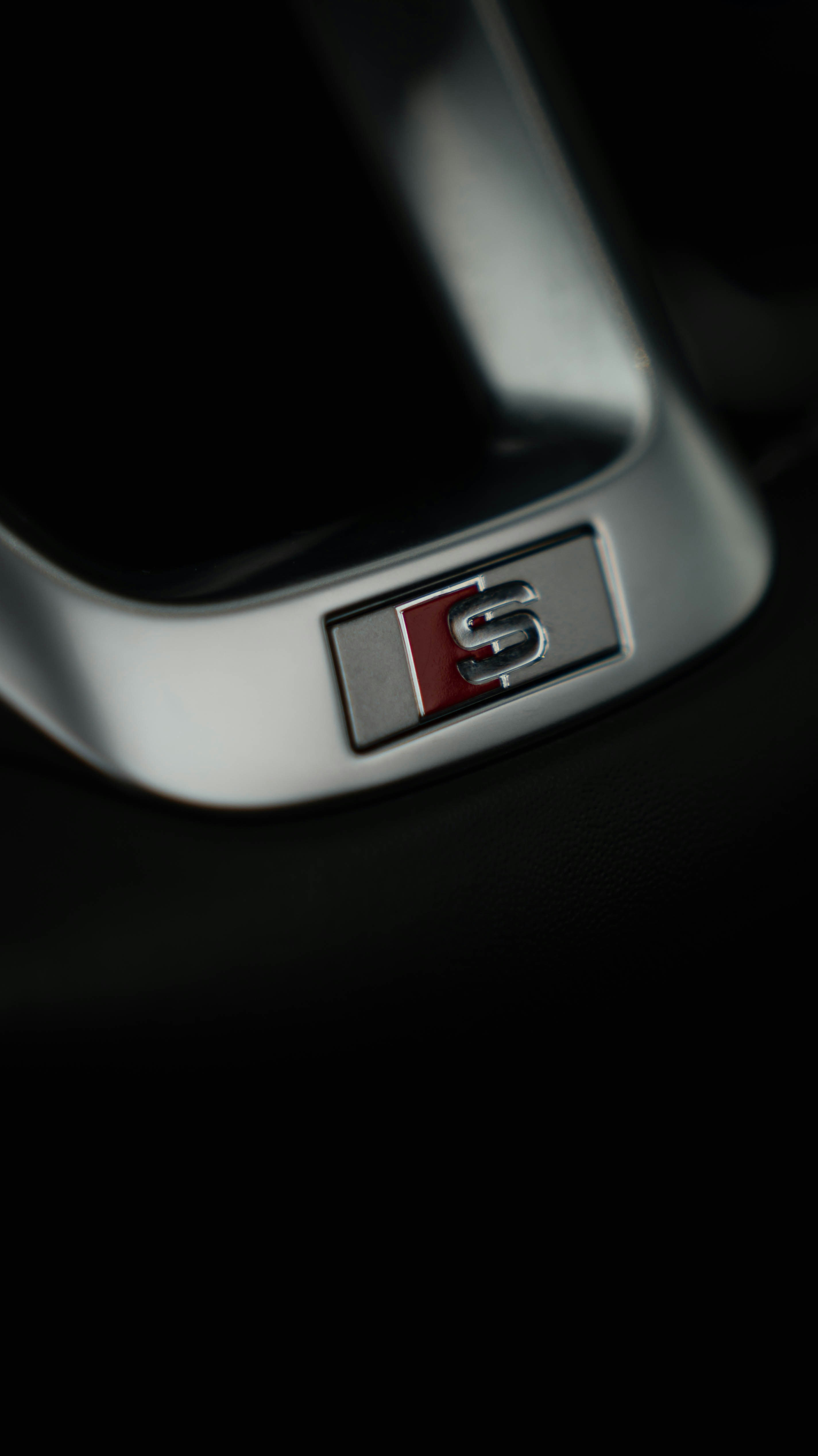 Close-up of an audi s badge on a car interior.