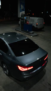 Dark sedan parked at a gas station at night.