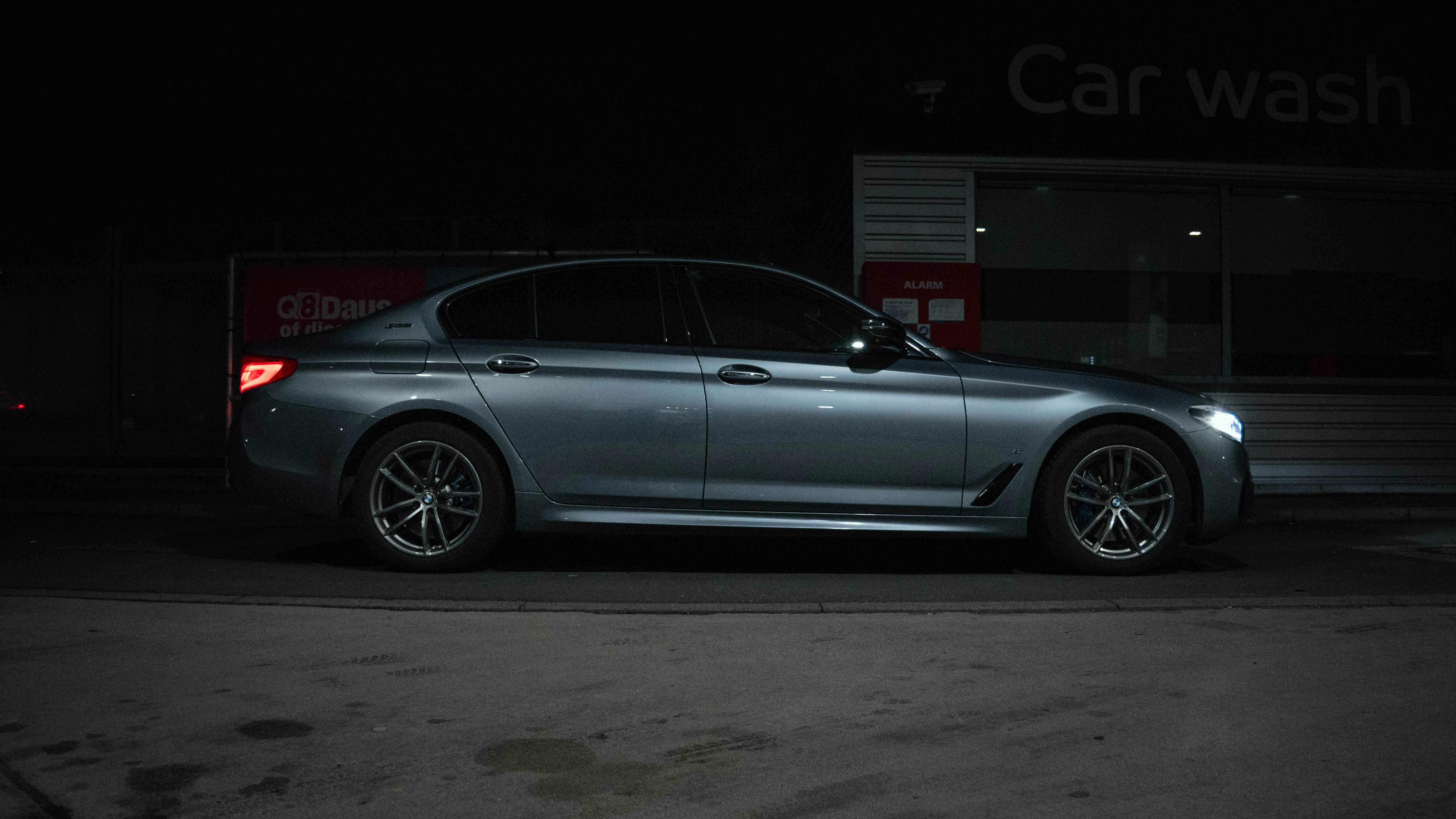 Un coche gris aparcado en un lavado de coches por la noche