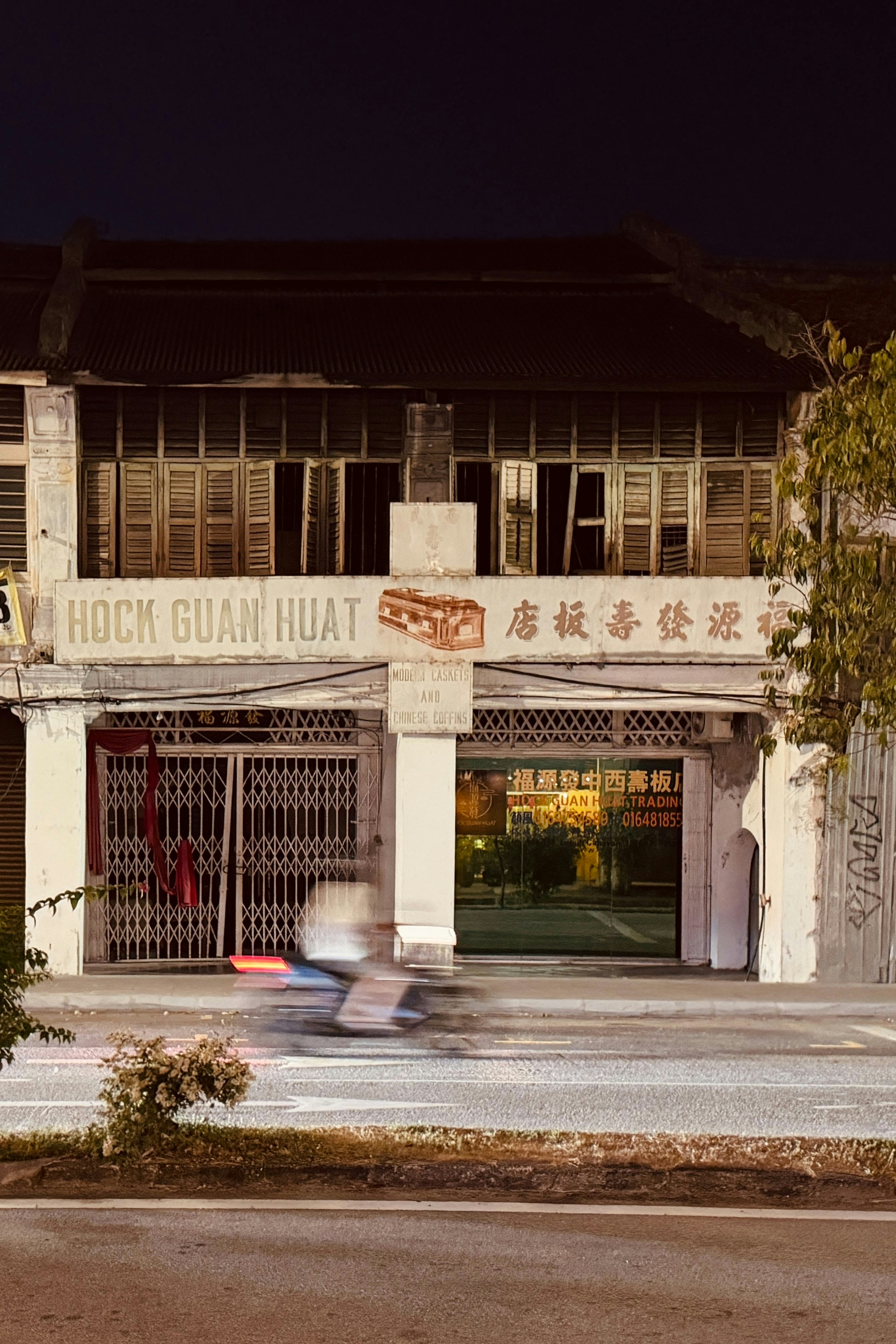 Old storefront with a motorcycle passing by at night
