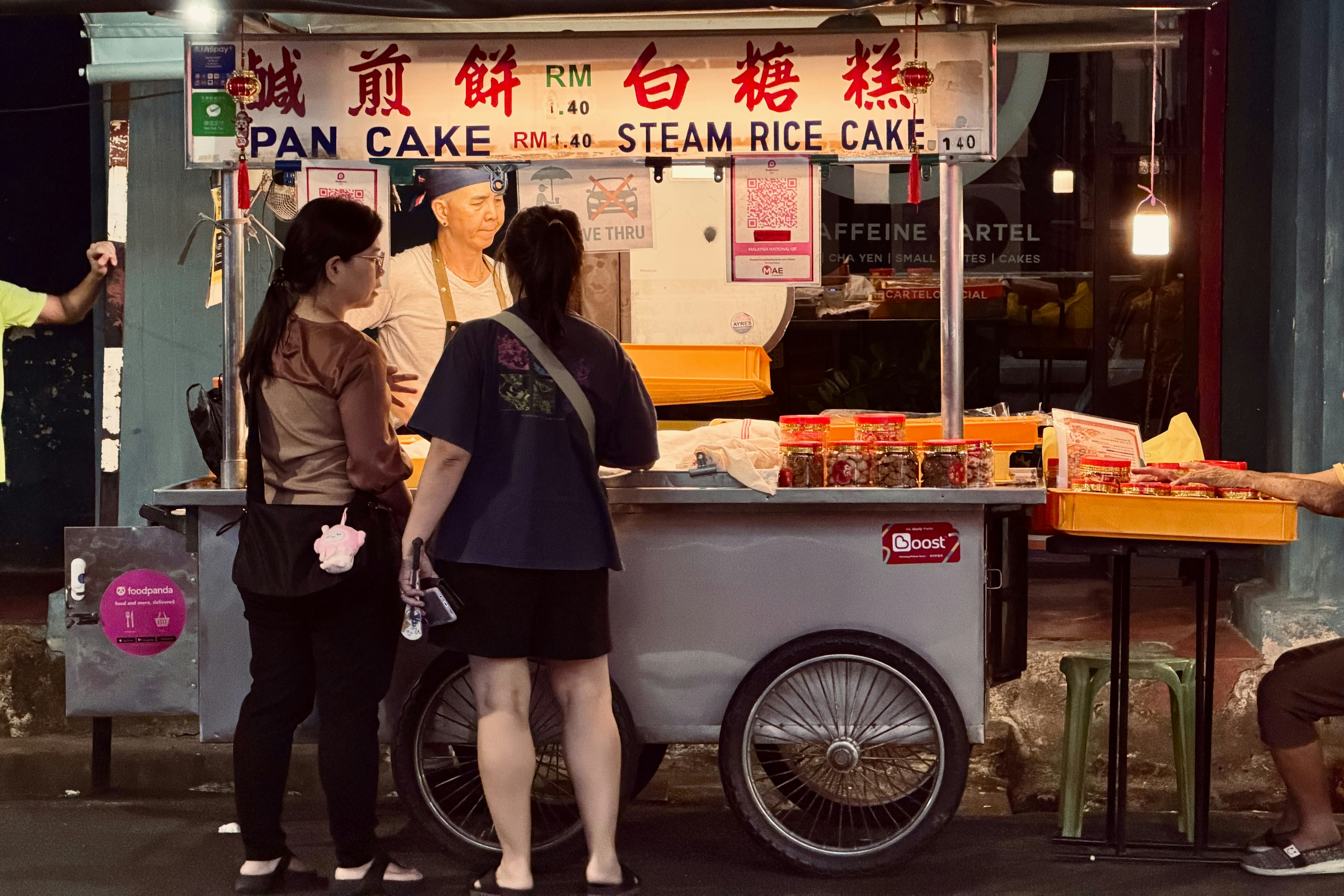 People buying food from a street vendor at night.