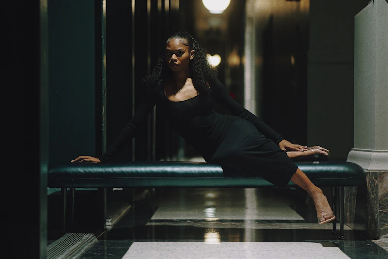 woman in a black dress posing on a bench