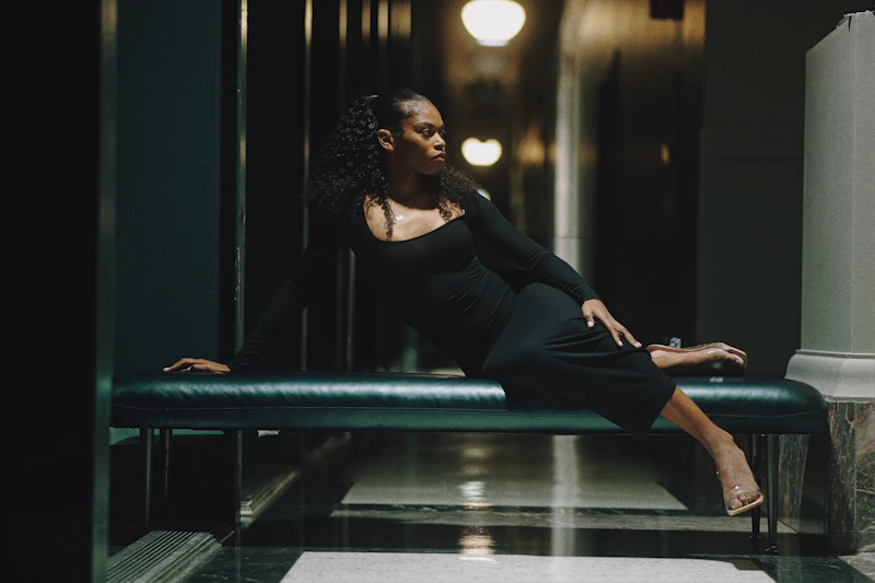 A stylish woman in a black dress lounging on a chic green bench