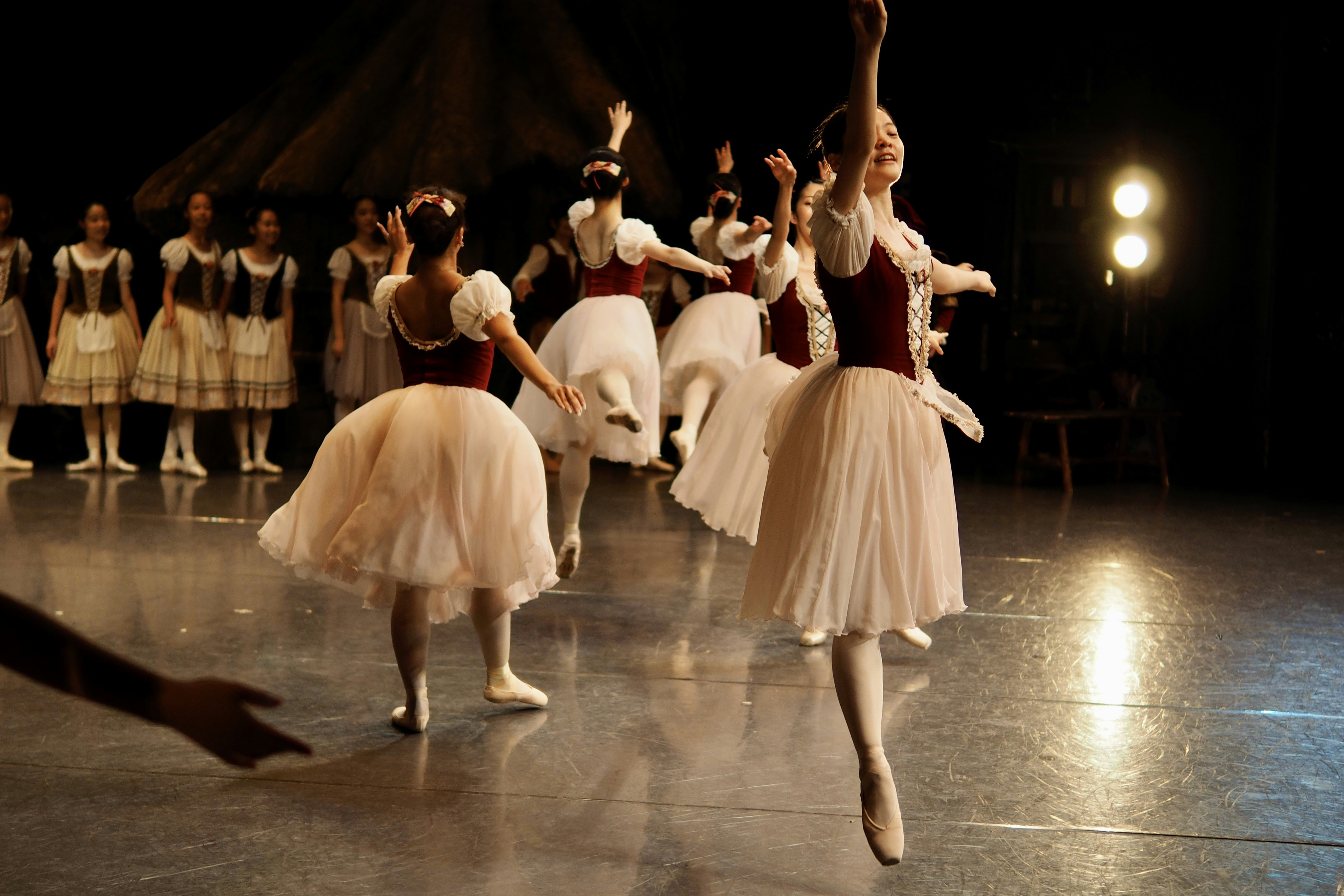 Balletttänzer treten auf einer Bühne mit dunklem Hintergrund auf.
