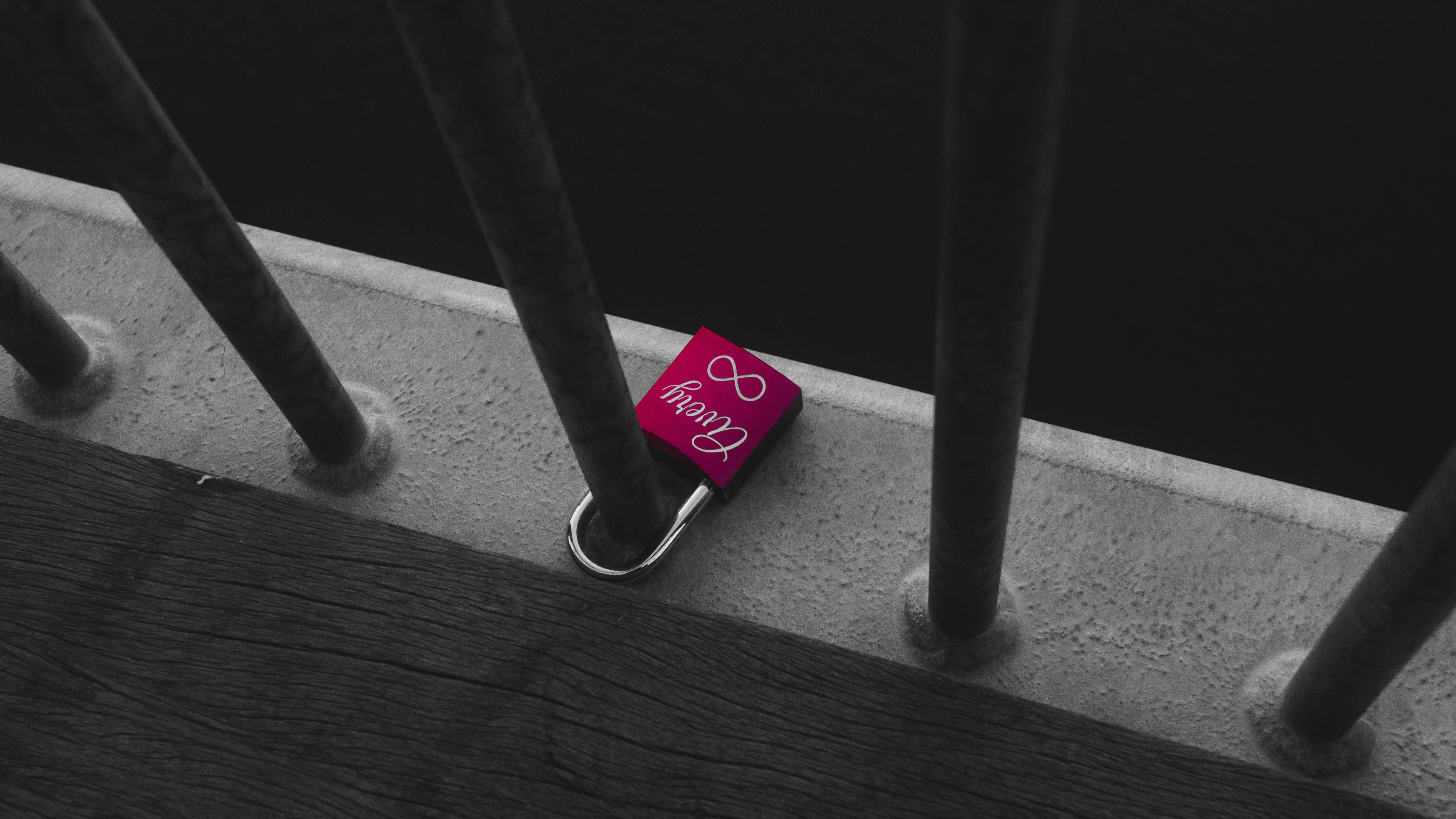 A pink lock with an infinity symbol attached to railing