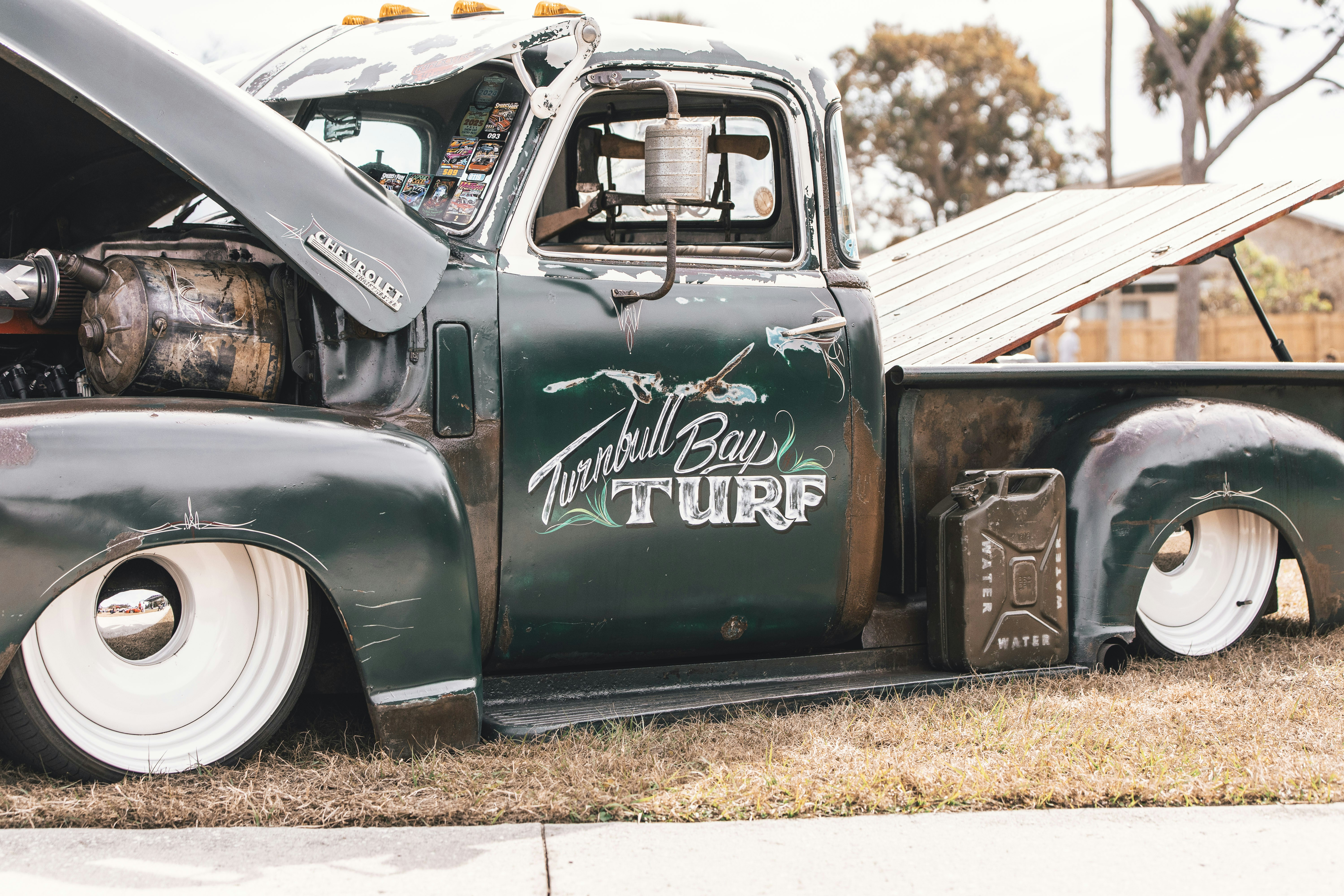 Vintage green pickup truck with lowered suspension and gas can.