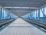 Modern airport walkway with glass walls and moving walkway