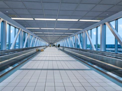 Modern airport walkway with glass walls and moving walkway