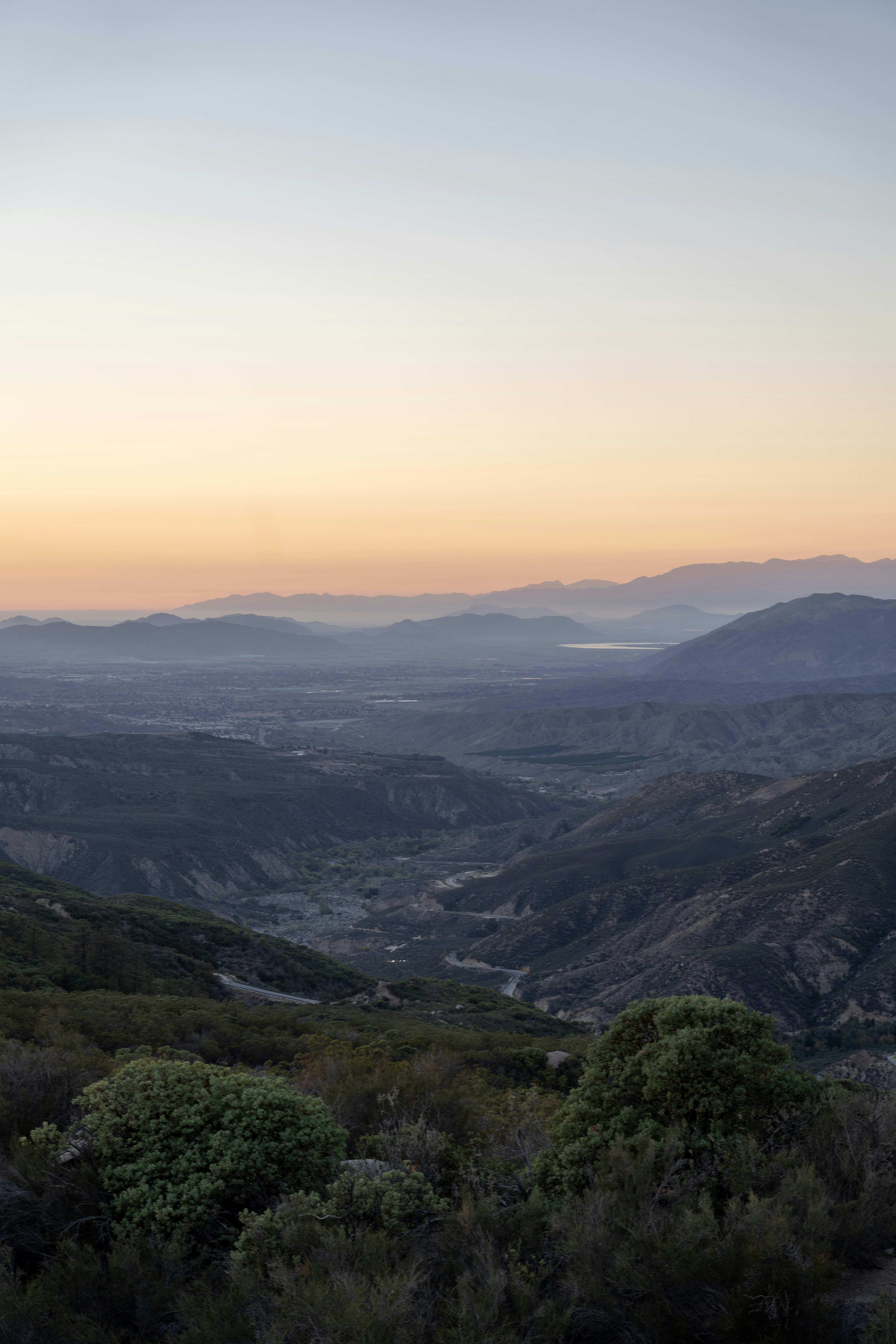 Mountain valley landscape at sunrise with soft pastel sky