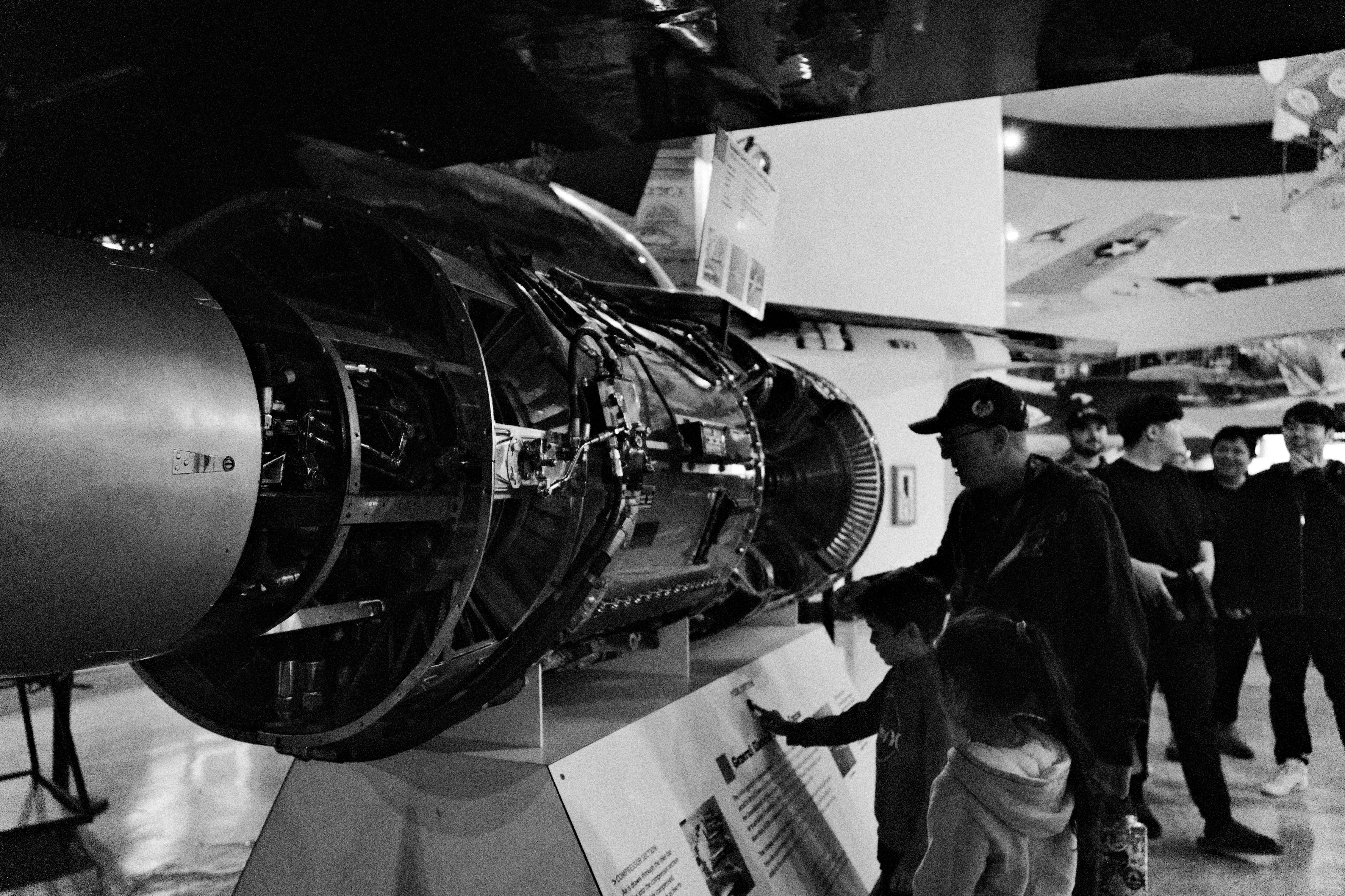 People observe a large aircraft engine on display.