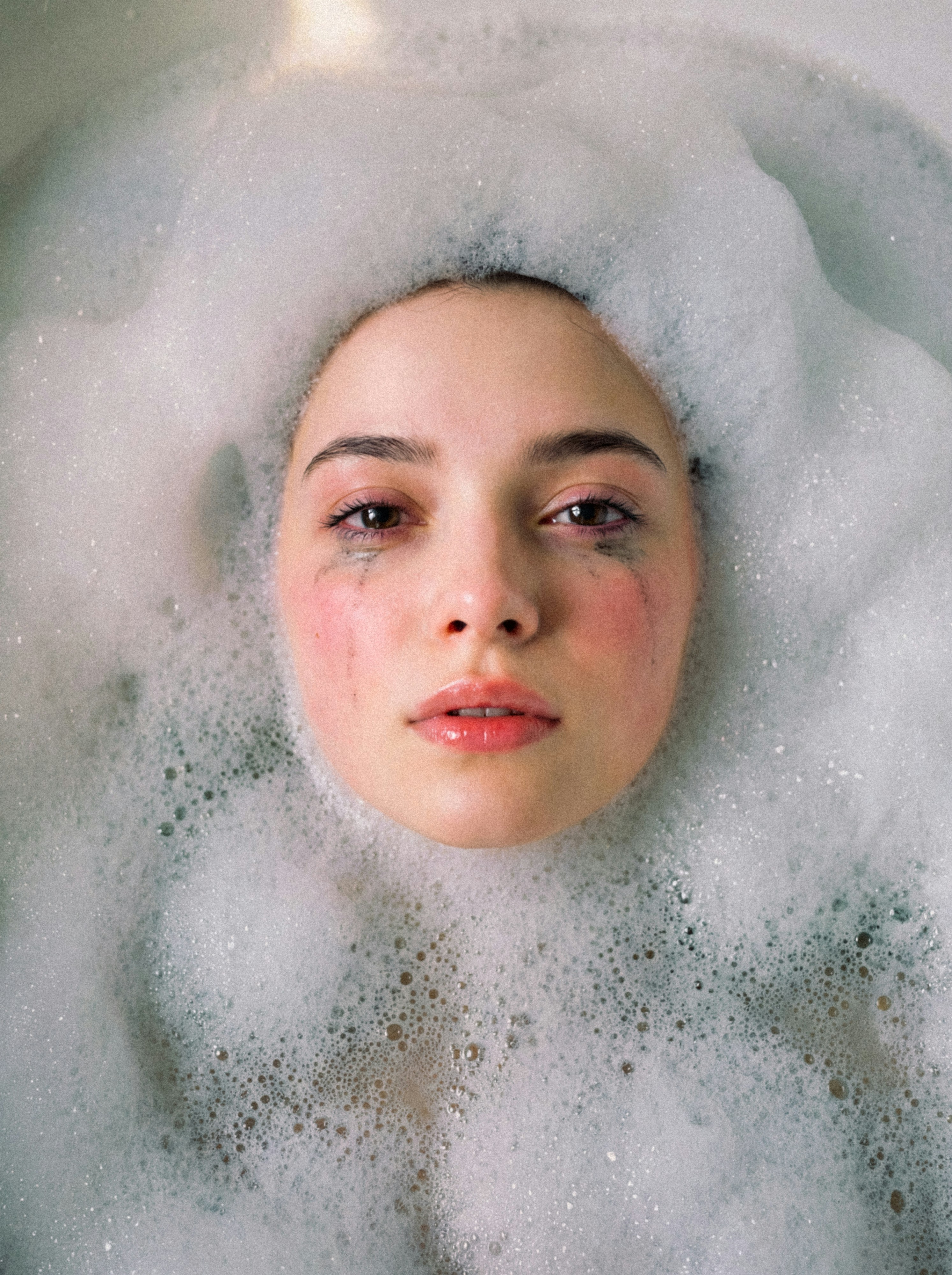 Woman's face submerged in bath bubbles