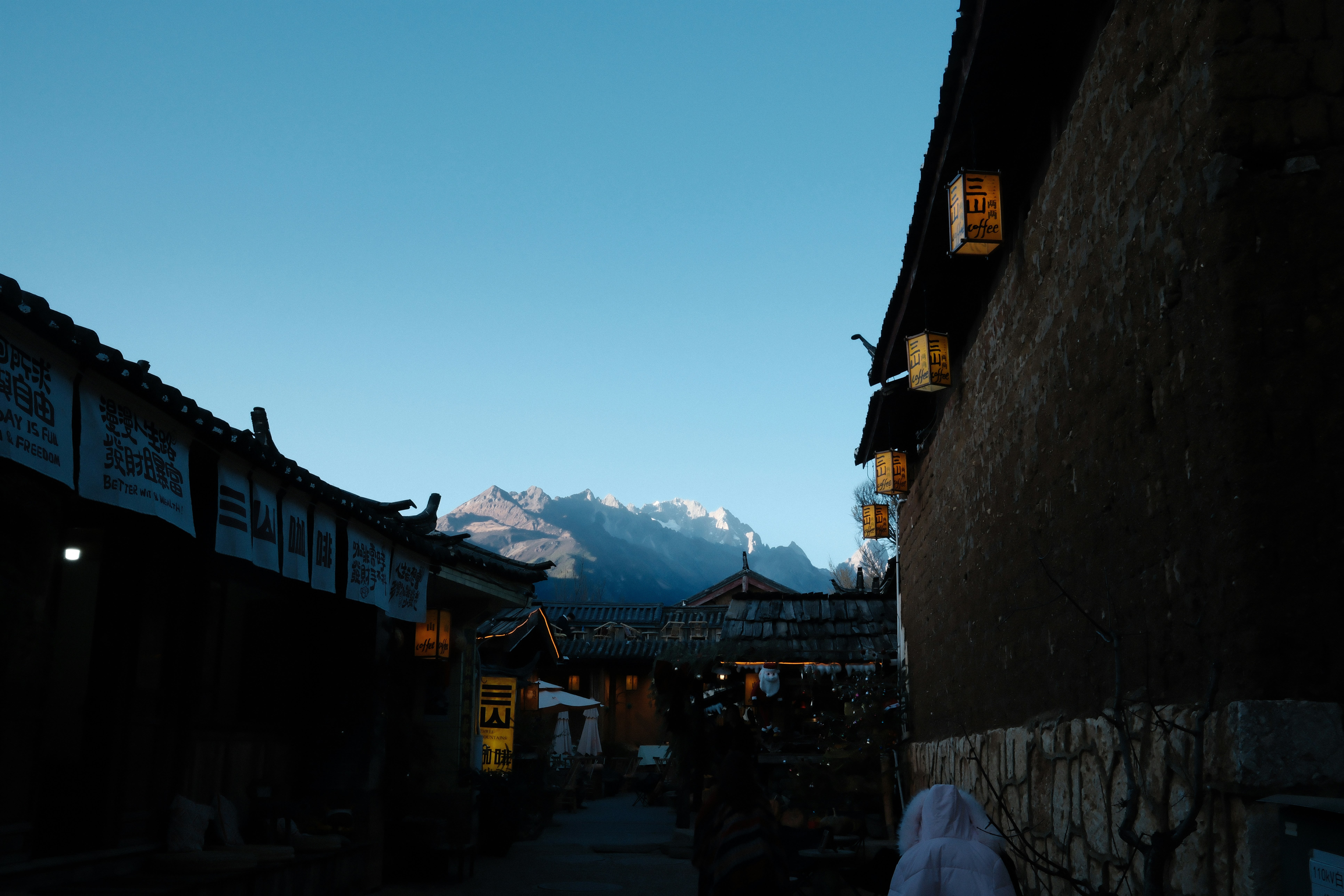 Mountain peaks visible through a narrow street at dusk