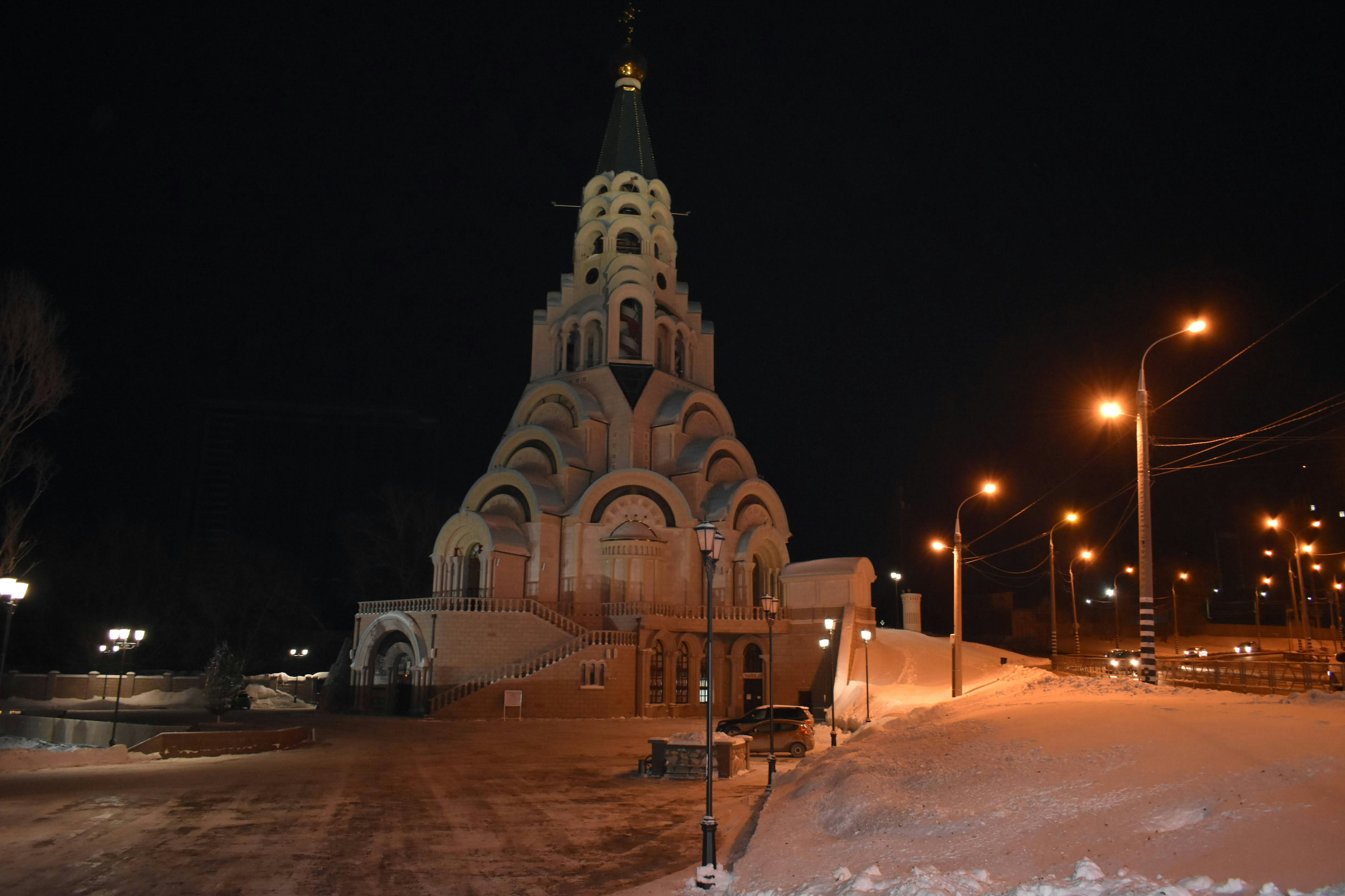 Church illuminated at night with snow-covered ground.