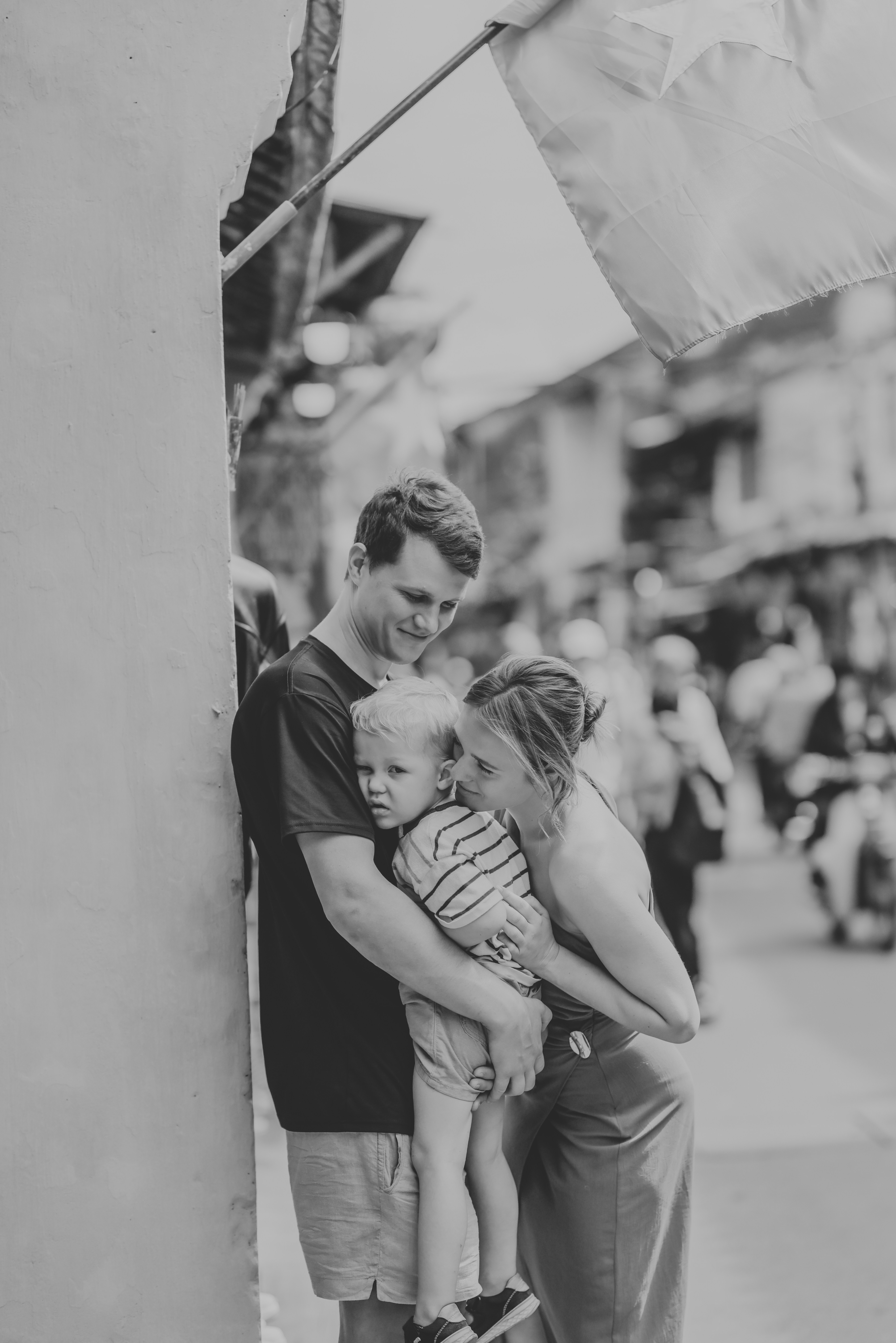 A family of three embracing on a street.