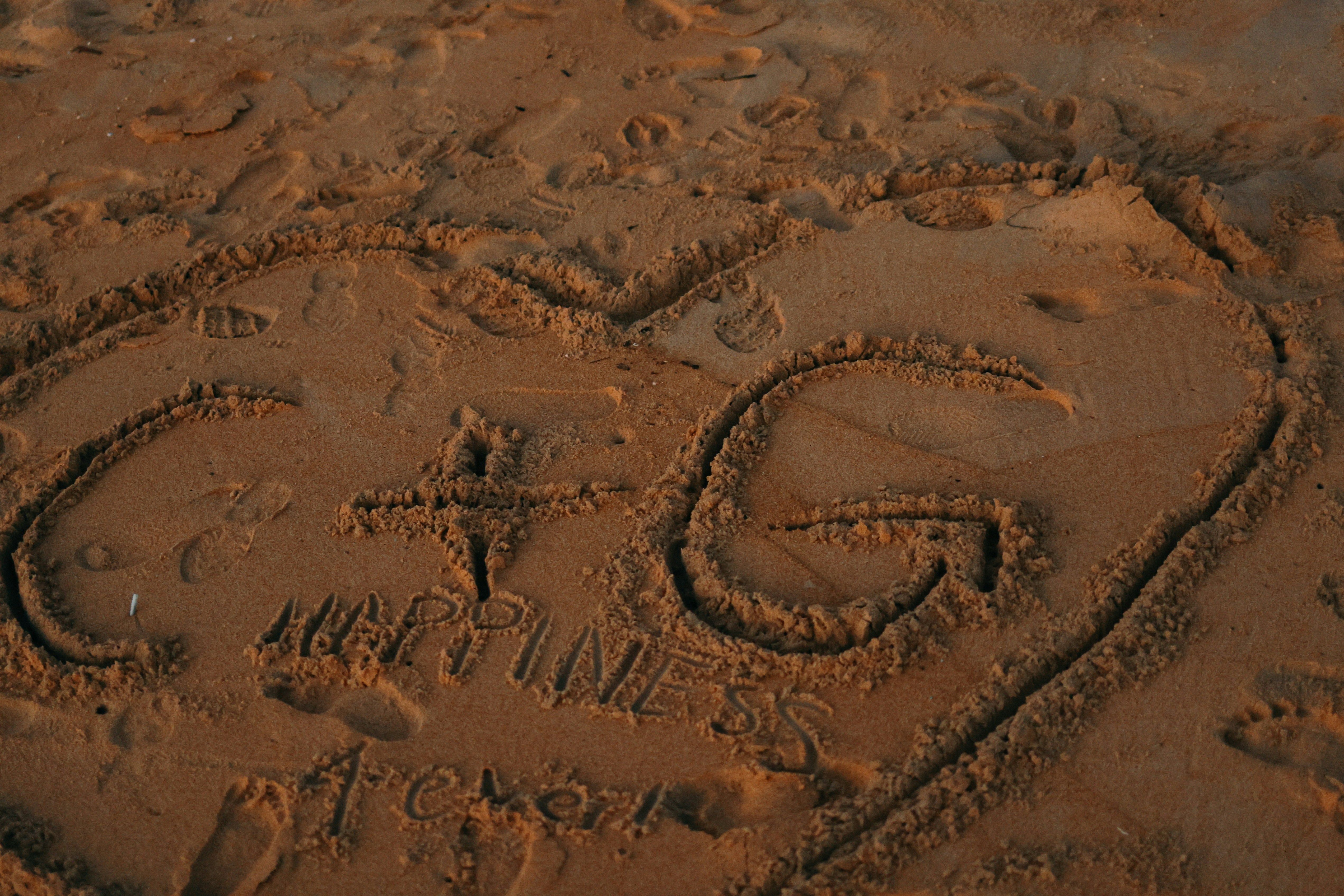 Corazón dibujado en arena con iniciales y nombres