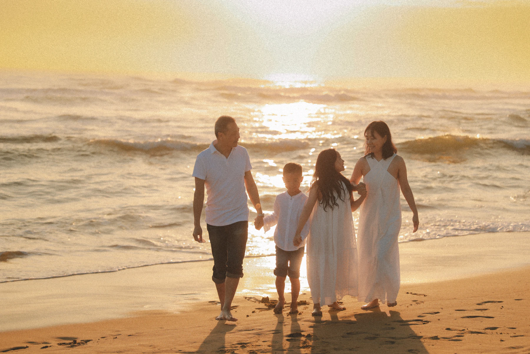 Family walking together along the beach at sunset