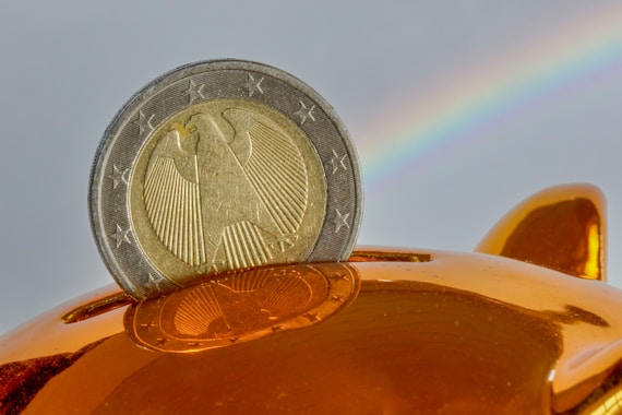 A coin being placed into a golden piggy bank.