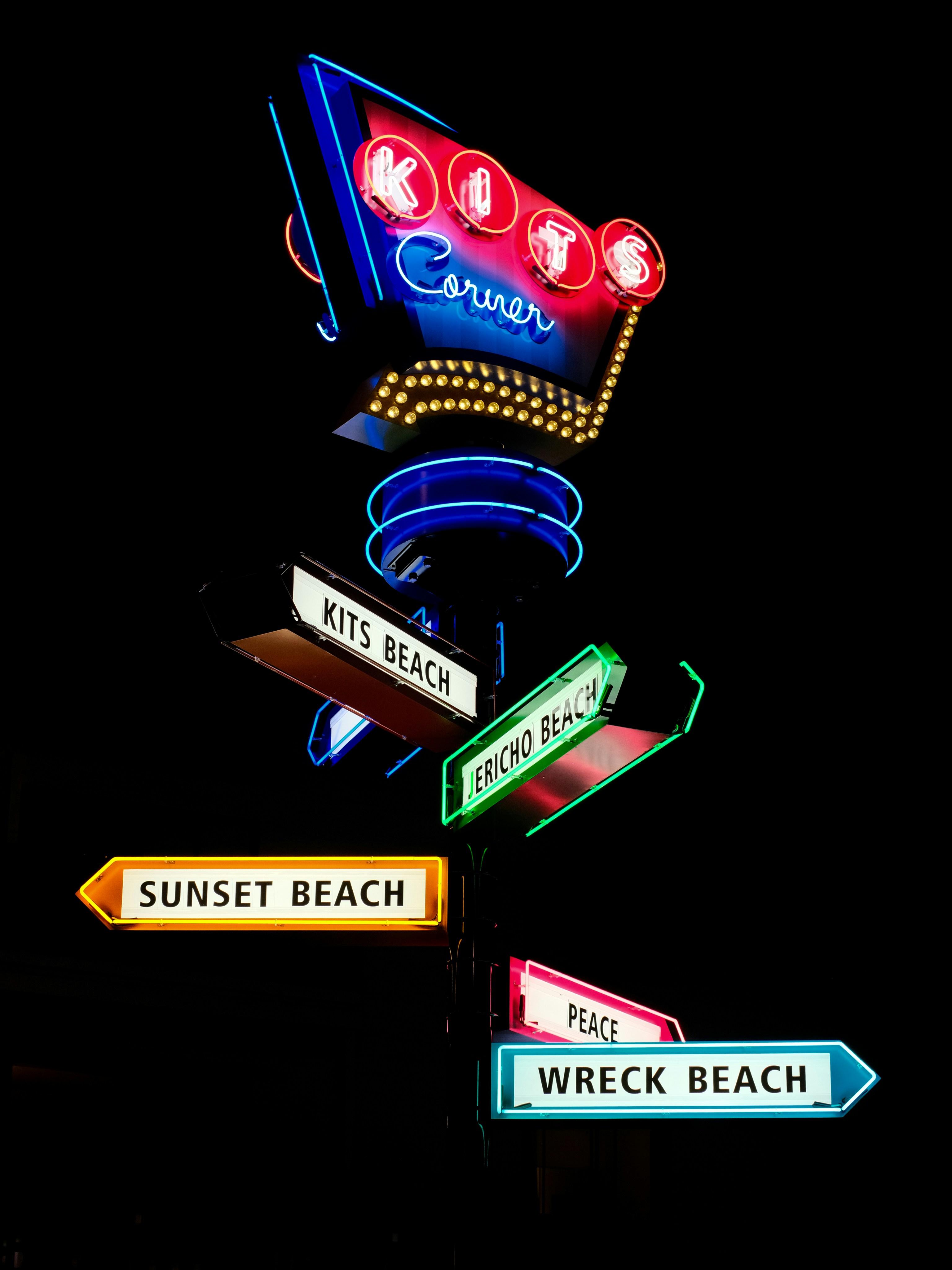 Neon sign with directional arrows at night