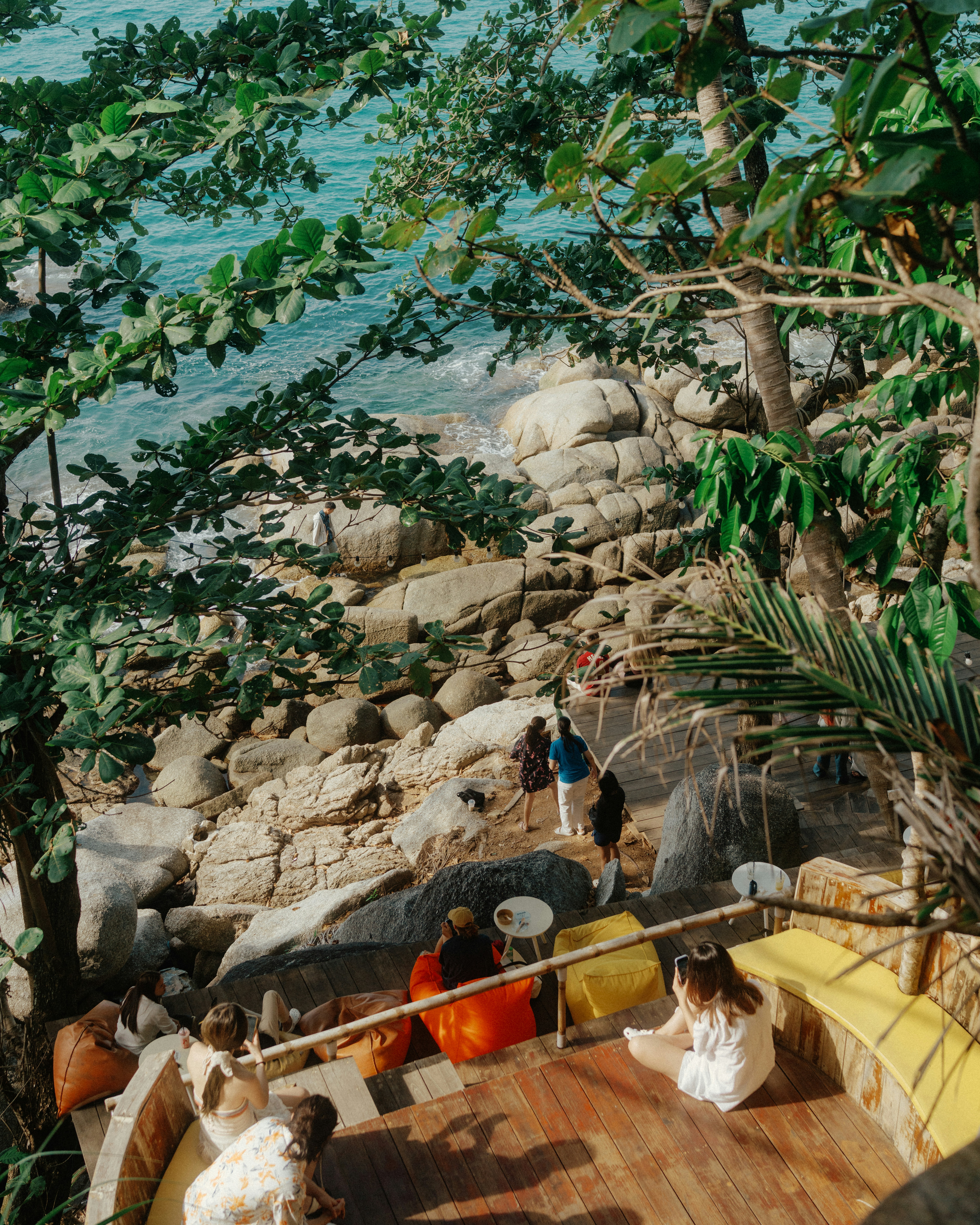 People relaxing by a rocky beach with turquoise water. - 相关推荐