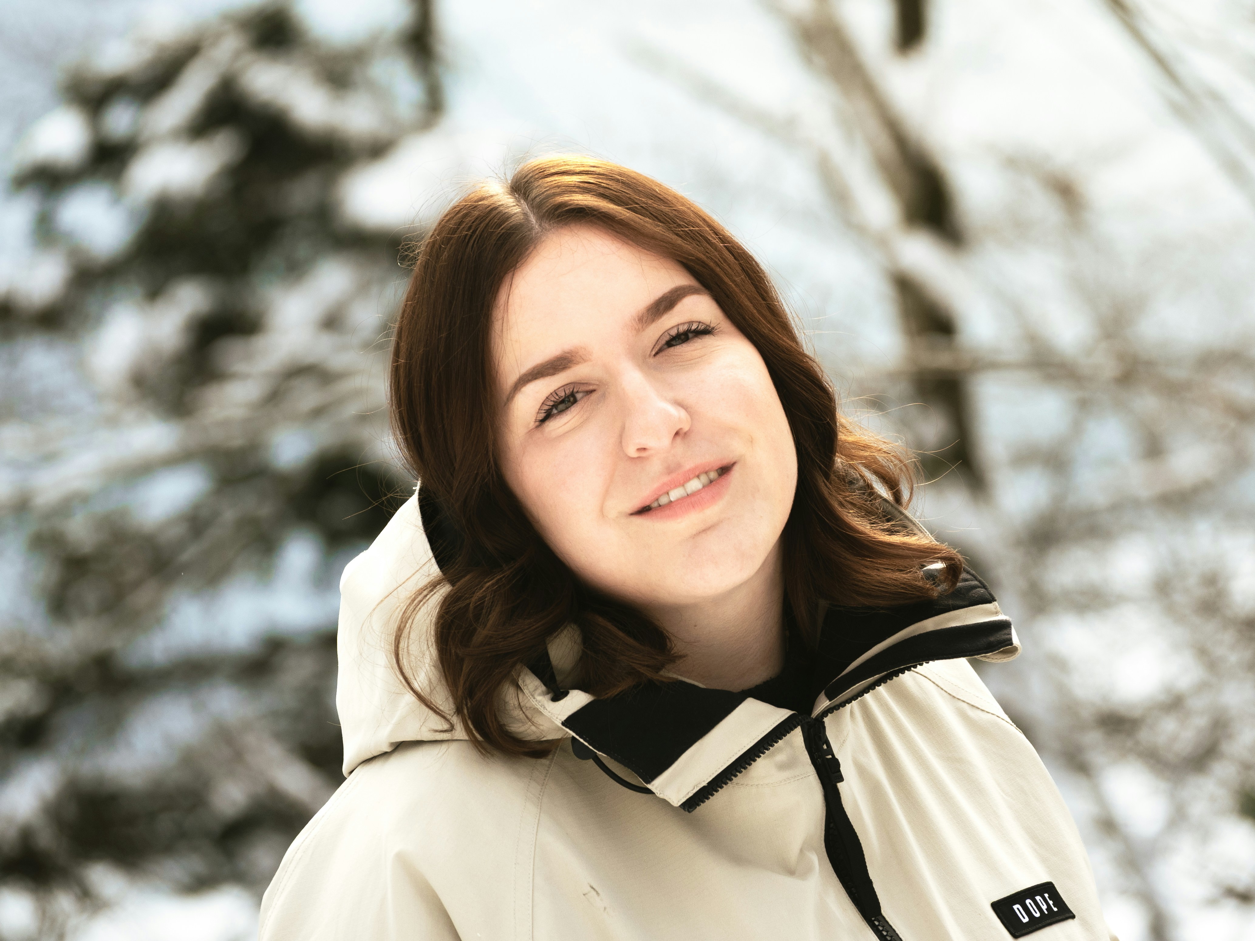 A young woman in a winter jacket smiles outdoors.