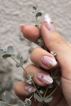 Woman's hand with ornate nails holding a delicate plant
