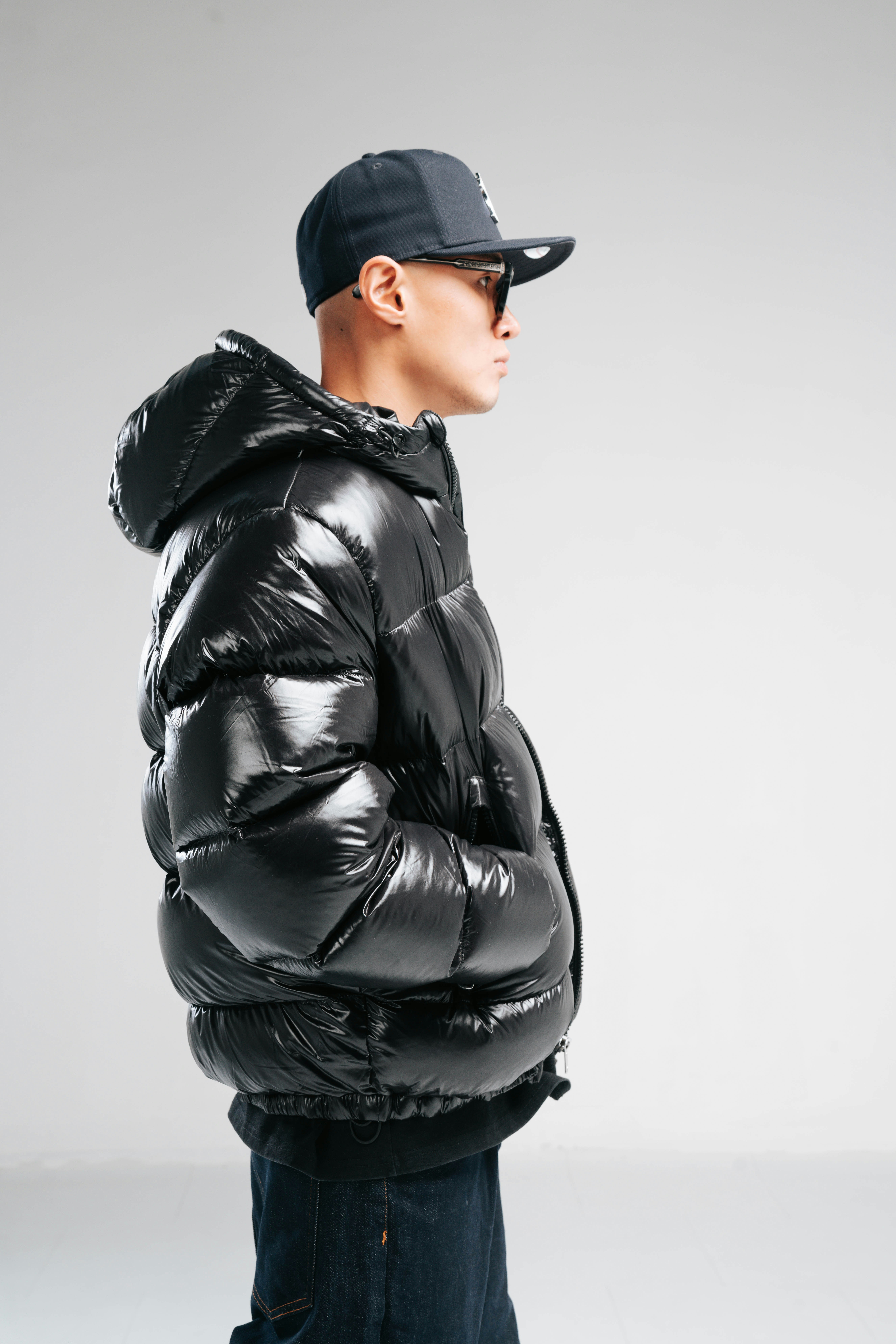 Man in shiny black puffer jacket and baseball cap